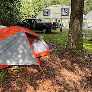 Cozy campsite behind the greenhouse. Short walk to showers with hot water, bathroom with plumbing, and outdoor kitchen.