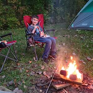 Enjoying hot dogs and smores by the fire.
