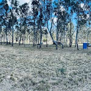 A panoramic view looking to the south. The sites run right to left in between the two tree lines. The blue box on the right is a toilet. The other toilet is next to the small building on the left side of the picture.