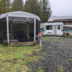 A view of the all hooked up site. Water and electrical hook-ups by the barn. Mostly gravel, but a little grass with a fire pit and a picnic table, which we set up our screened easy-up next to.