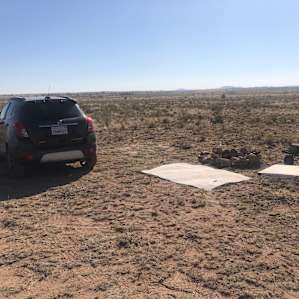 Campsite with mat, table & campfire.