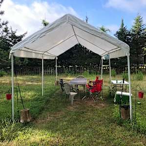Open-sided tent in the field with picnic table.