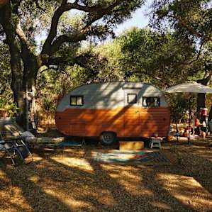 The camper located under the oak trees.