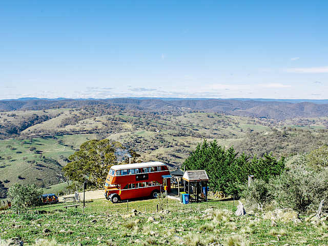 Red double-decker bus cabin overlooking rolling green valley and distant hills