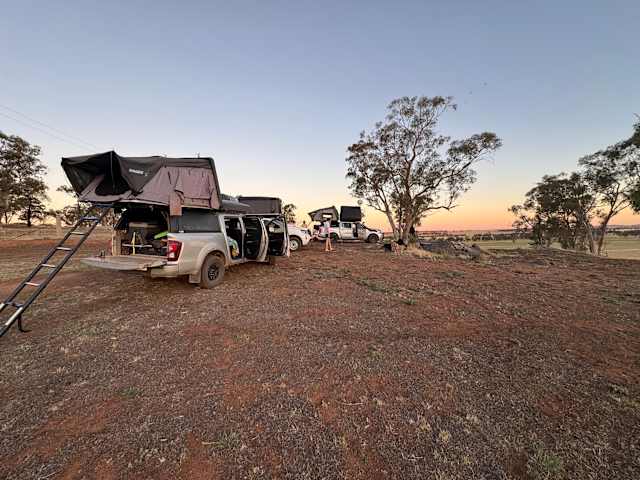 Two 4WDs with rooftop tents parked on a ridge at sunset, golden sky behind