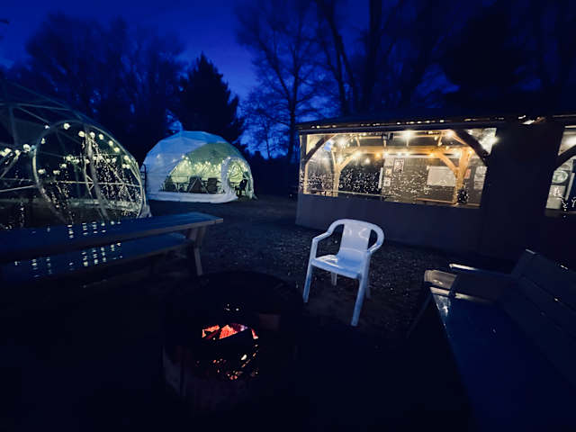 Glowing geodesic domes and fire pit at twilight with string lights