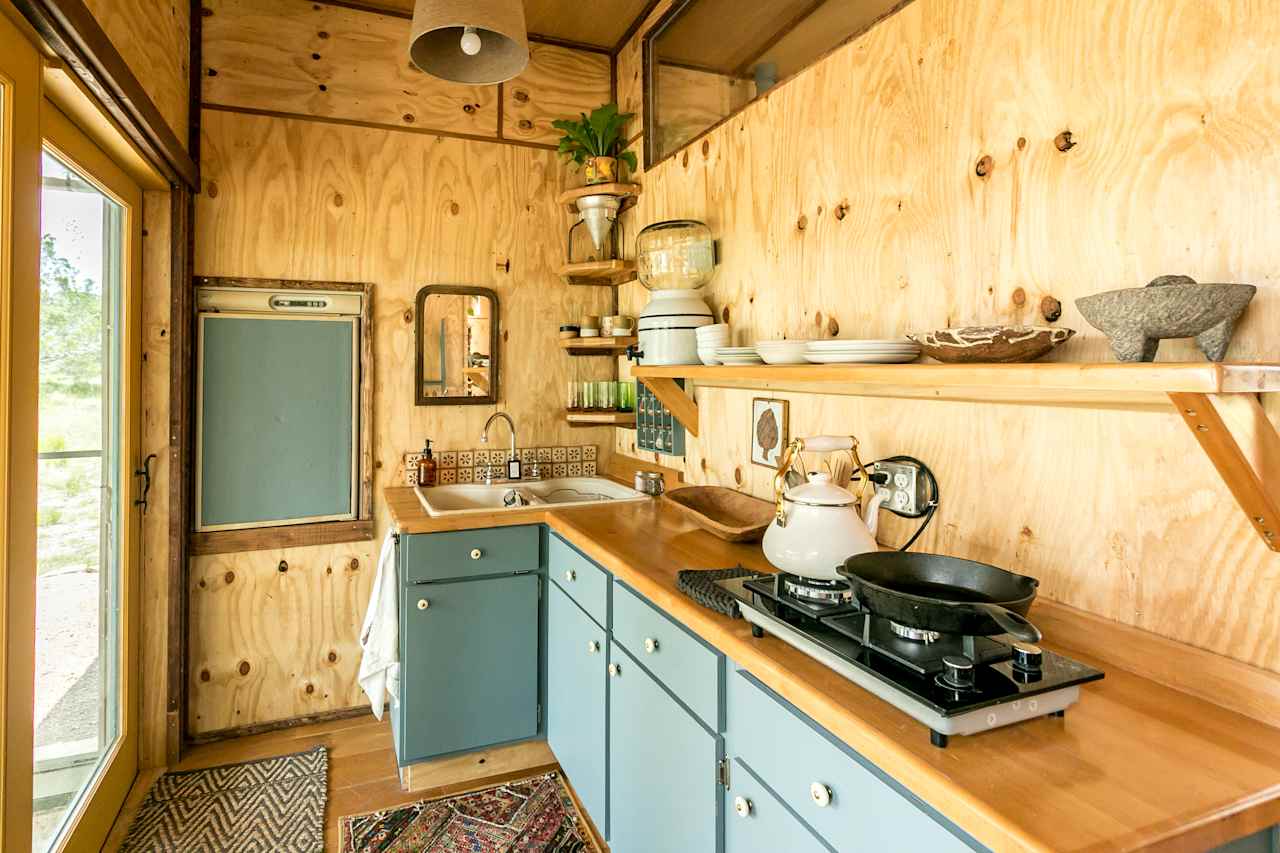 The kitchen features a 5.5 cu refrigerator/freezer, filtered rain water, a 2 burner stovetop, all dishes/utensils/pots and pans/spices.