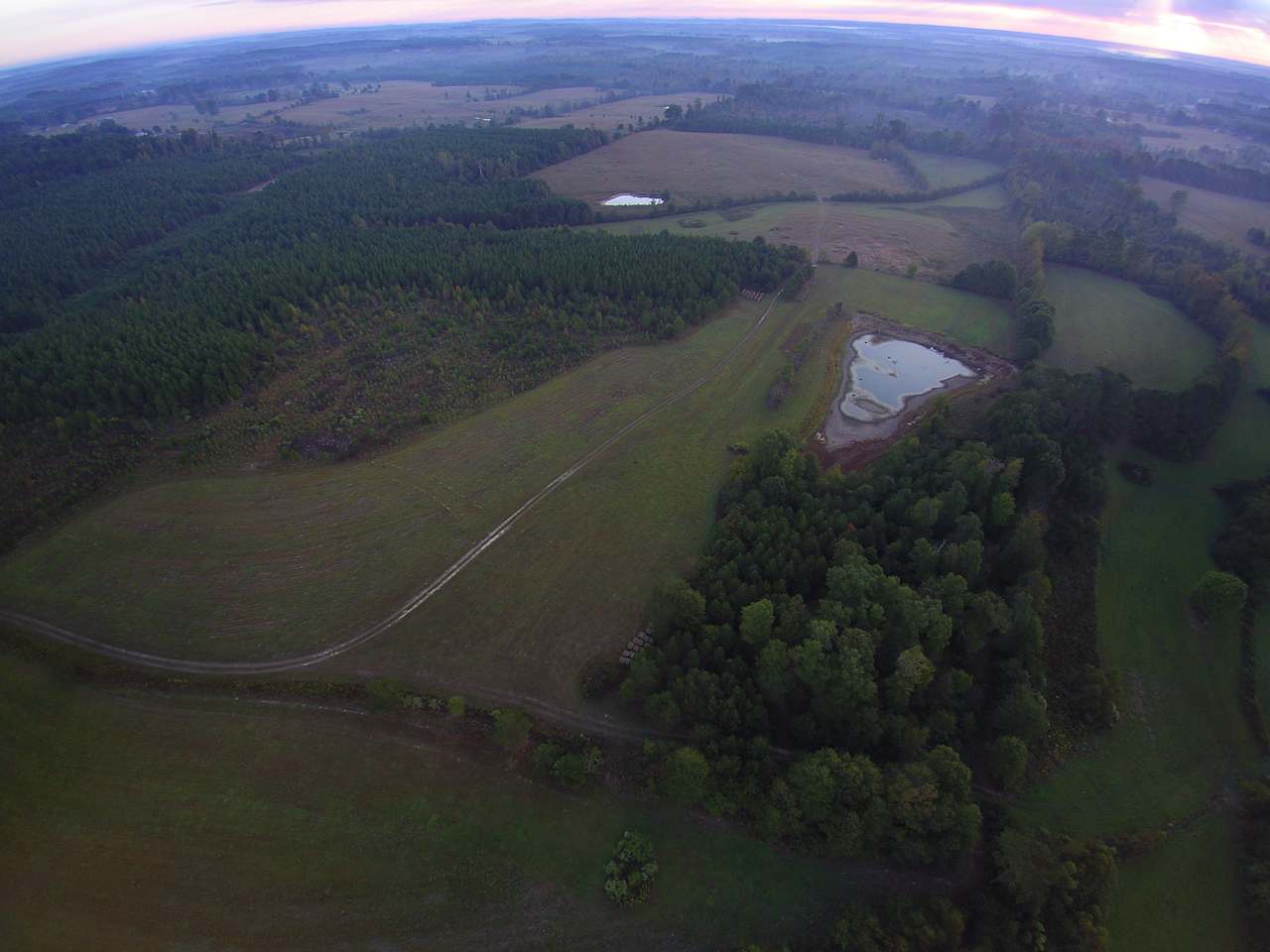 Drone shot from above house showing pond and pasture