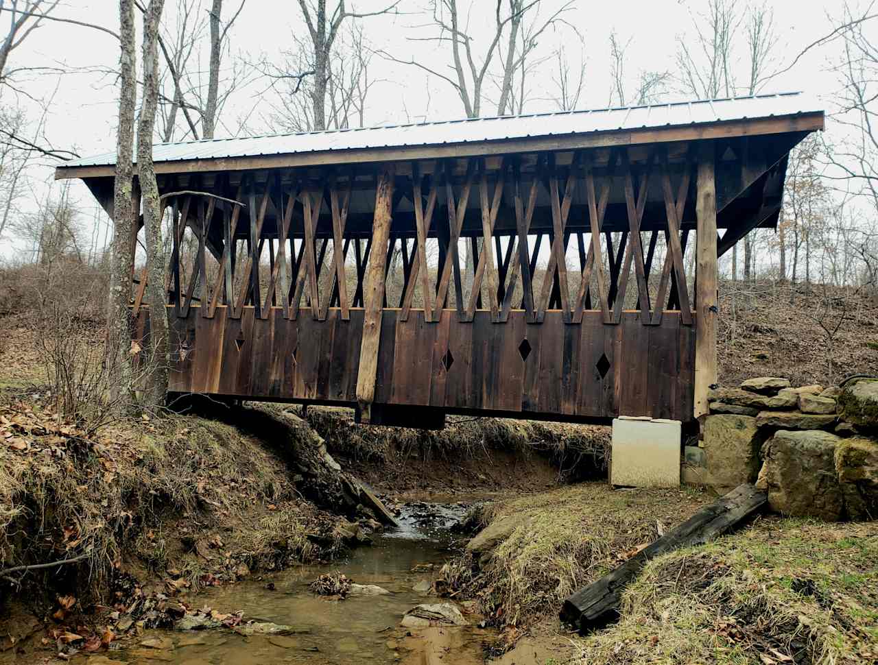 The historic restored covered bridge over the creek that brings you from the parking area to the large, shared pond and camping area.