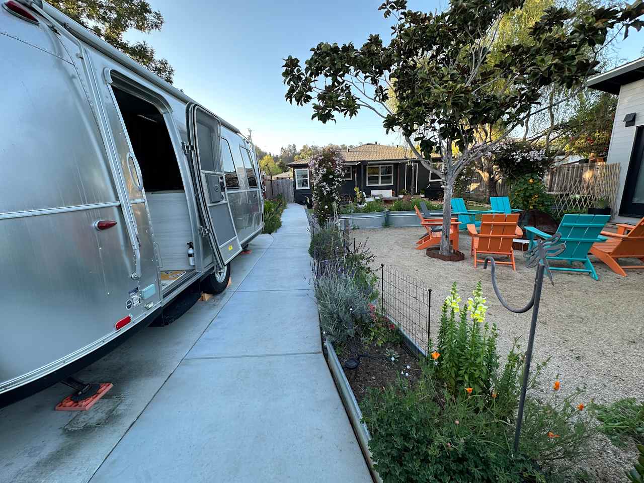 The Airstream sits between the main front house and rear ADU in a large shared yard and garden. (This is the view from the back gate to the ADU, looking towards the shared yard, airstream, and firepit).