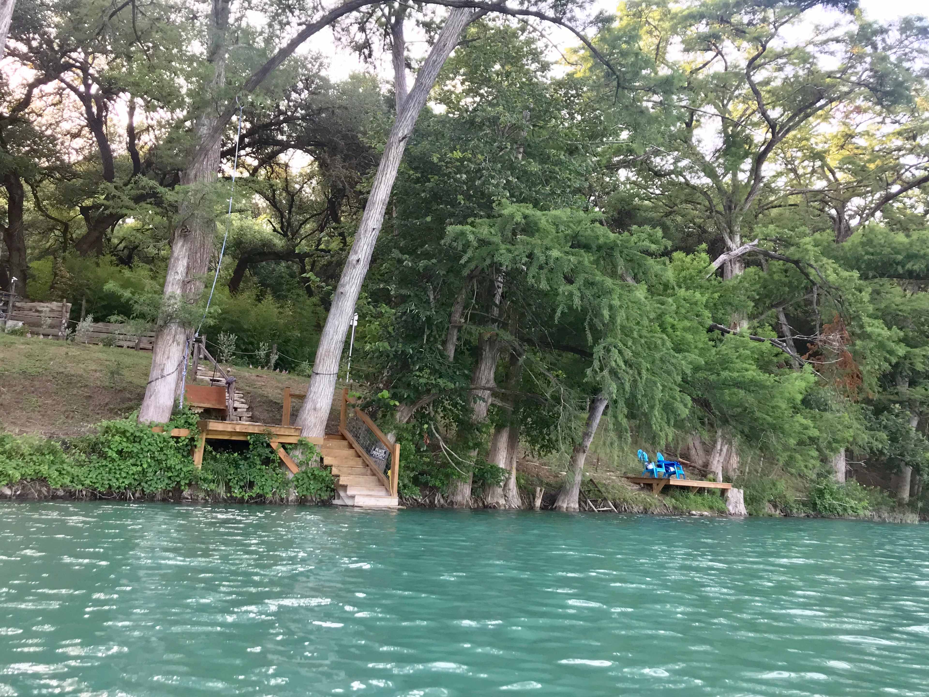 a water view showing both docks. the one on the left has rope swings, and steps for entering and exiting the river with floats, kayaks, SUPS, etc. The one on the right, is better suited for fishing, relaxing, meditating. There is a steel ladder adjacent to it.