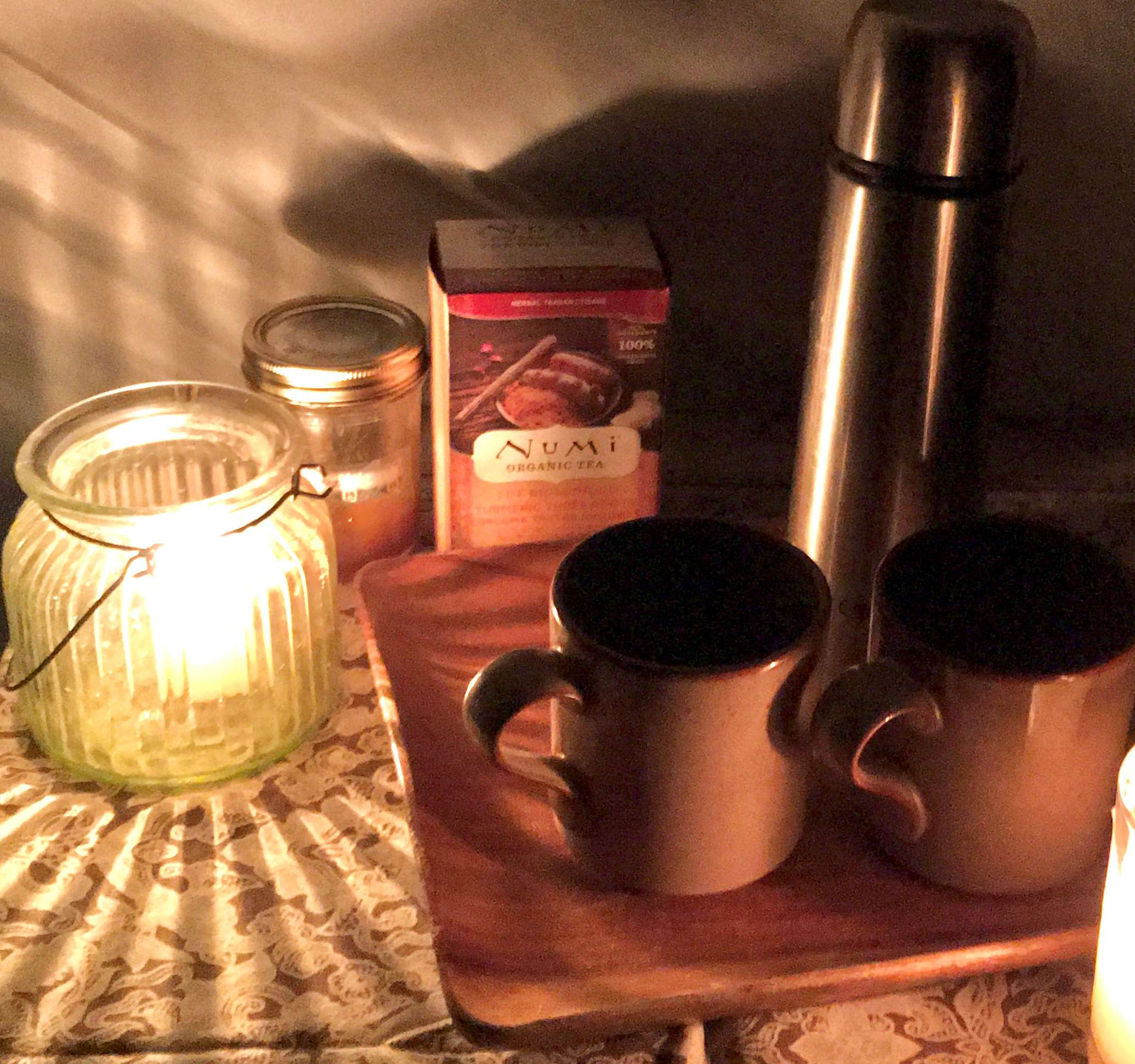 Warm thermos of herb tea and local sage honey at night by candlelight.