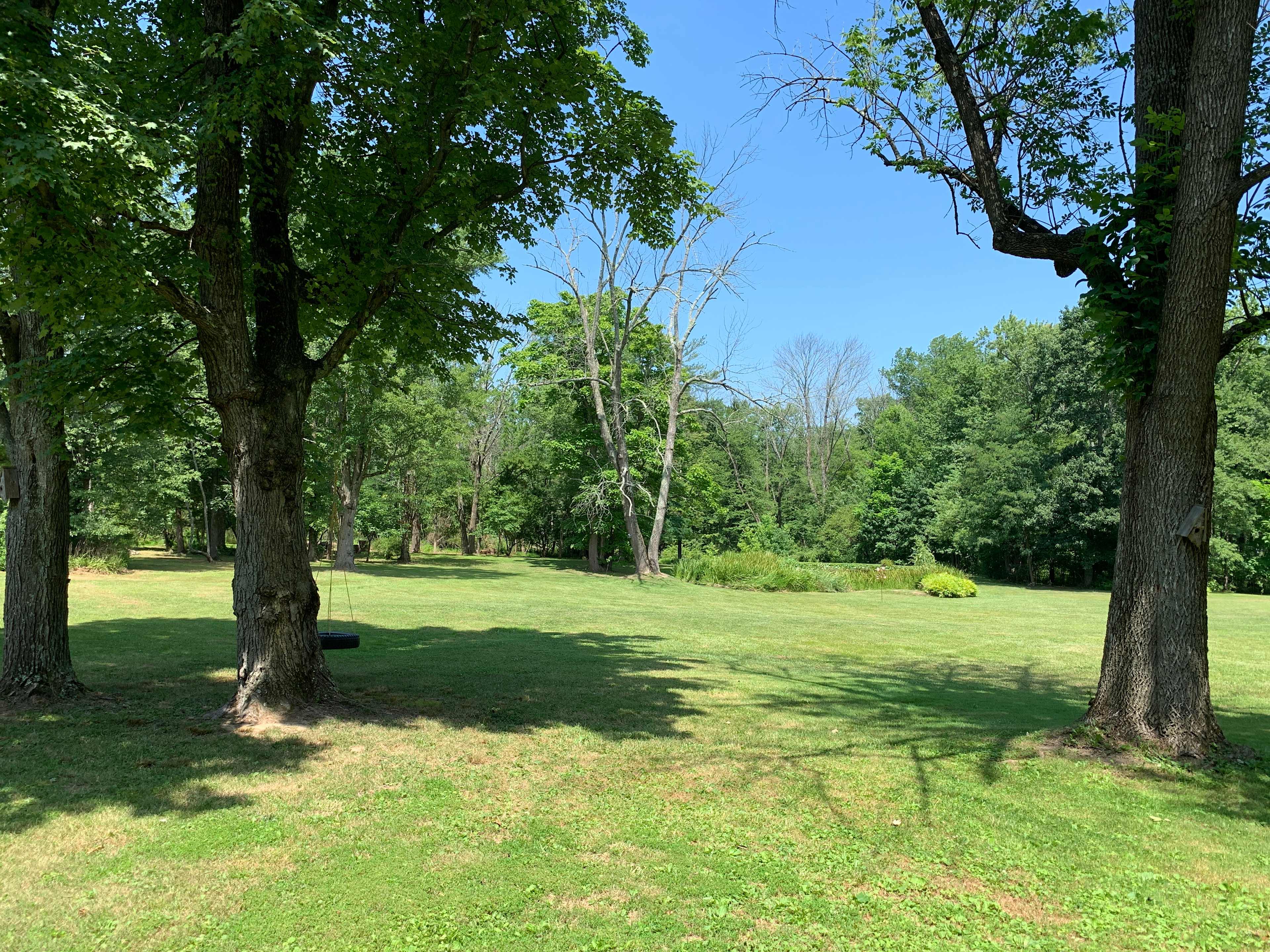 View of pond and tent area with woods in back ground
