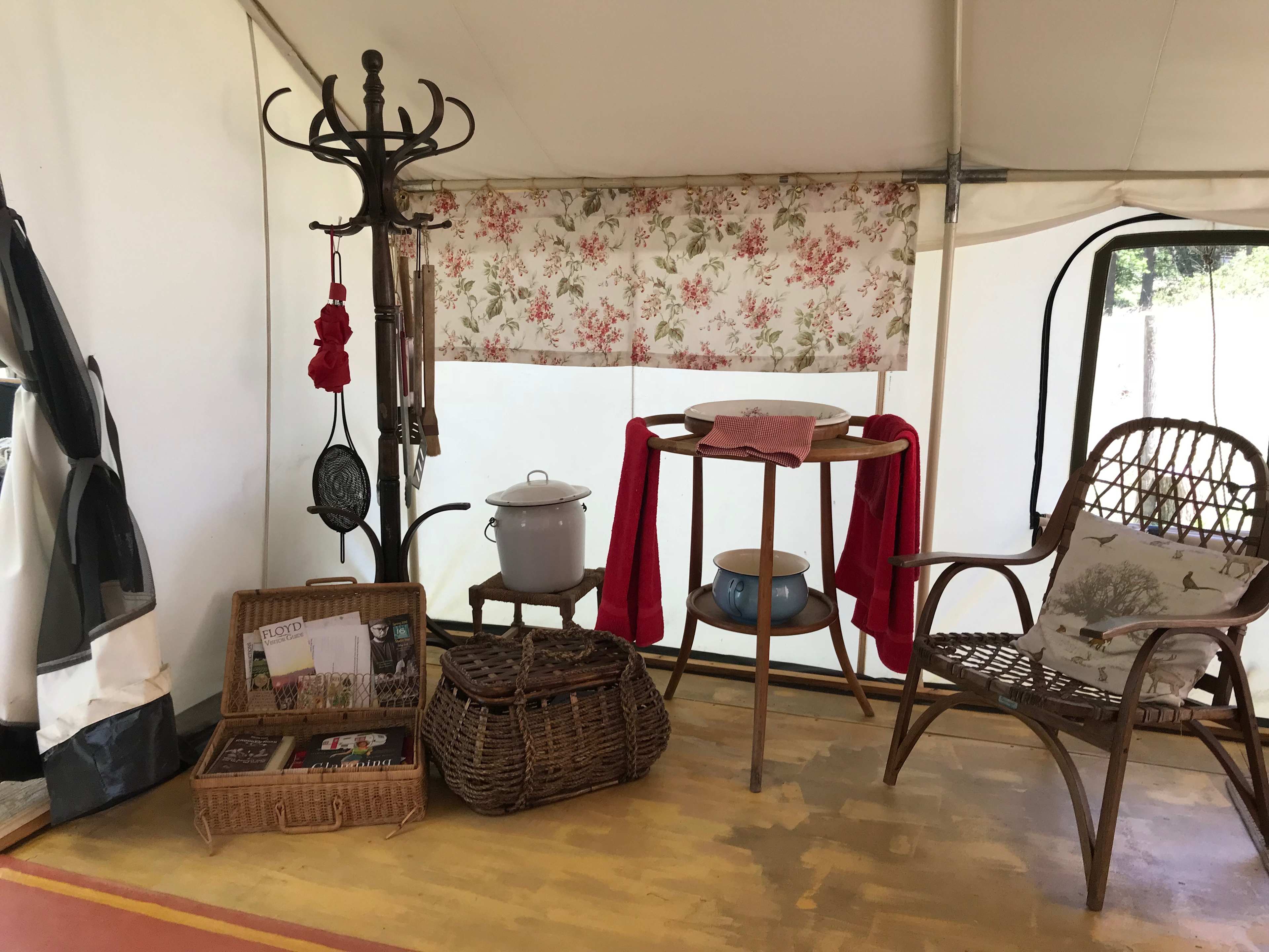 Inside the Lee Glamping Tent: towels, washing basin, and basket filled with information about the area, some games, and books. 