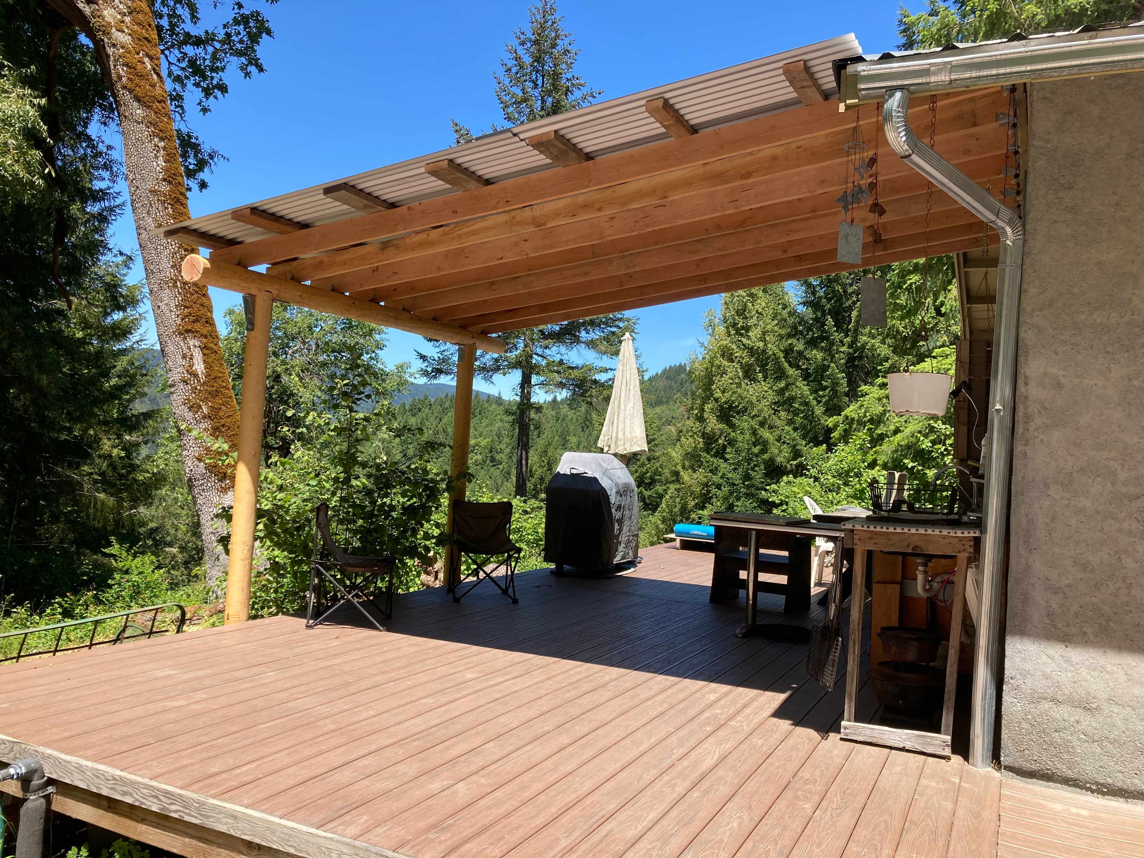 Outdoor kitchen has a BBQ, 2-burner camp stove, drinking water, cooler, and dishes.