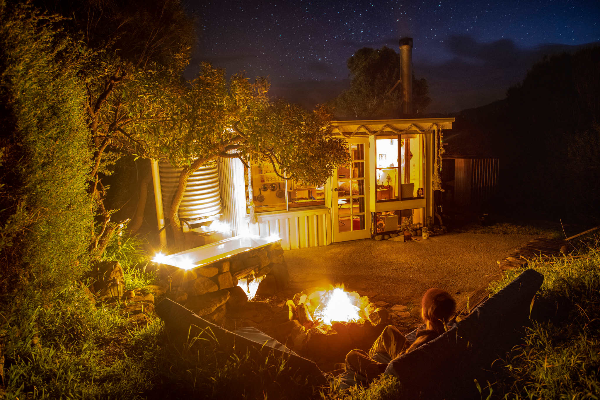 Sit on the outdoor lounge waiting for the fire under the bath to heat the water.  The heated rocks keep the water warm.      