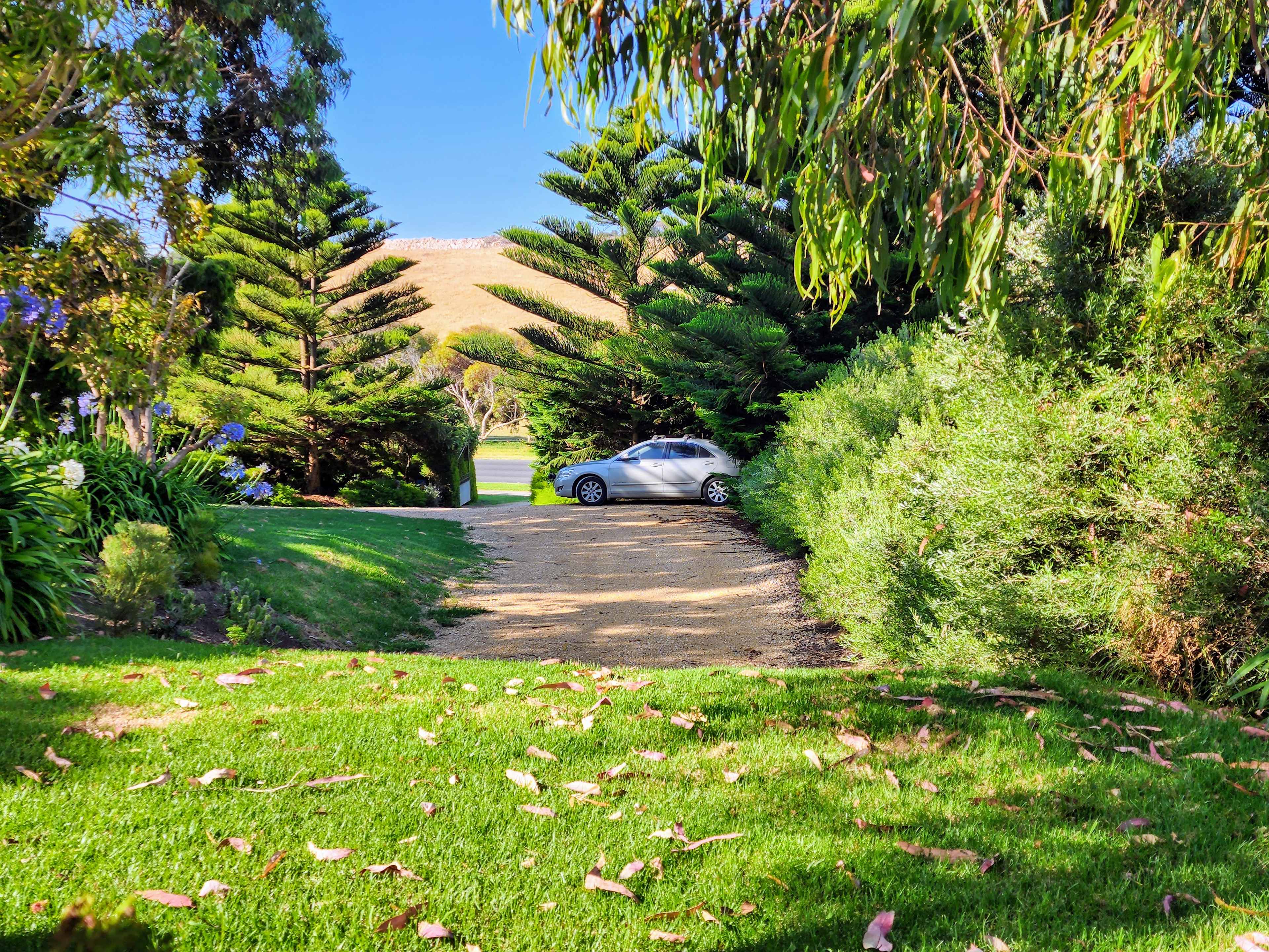 On the elevated grassy flat looking down to the large crushed sandstone area with the front gate in the distance to the left of the parked car