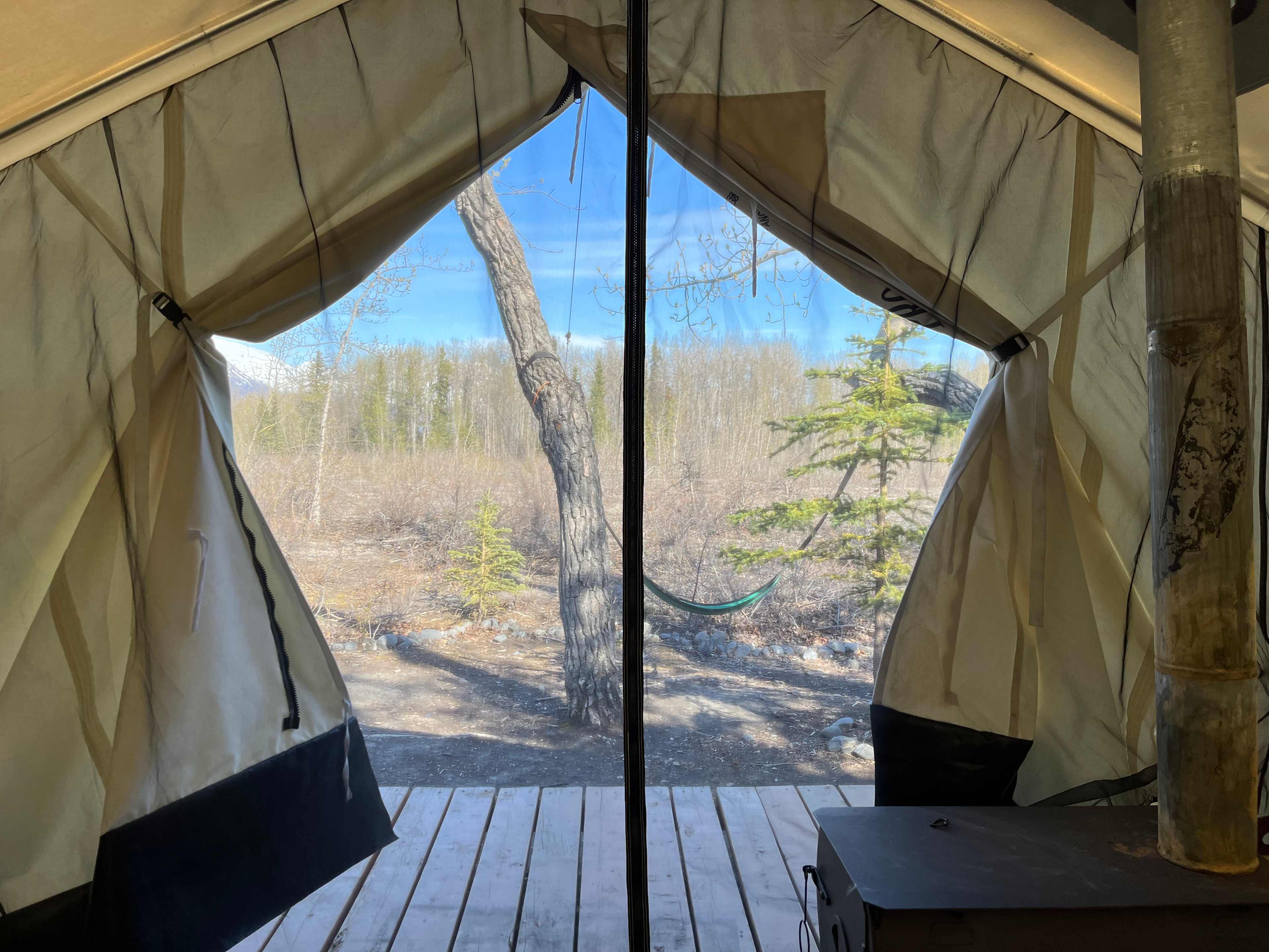 Looking out of the tent onto the porch with chairs and a swing.