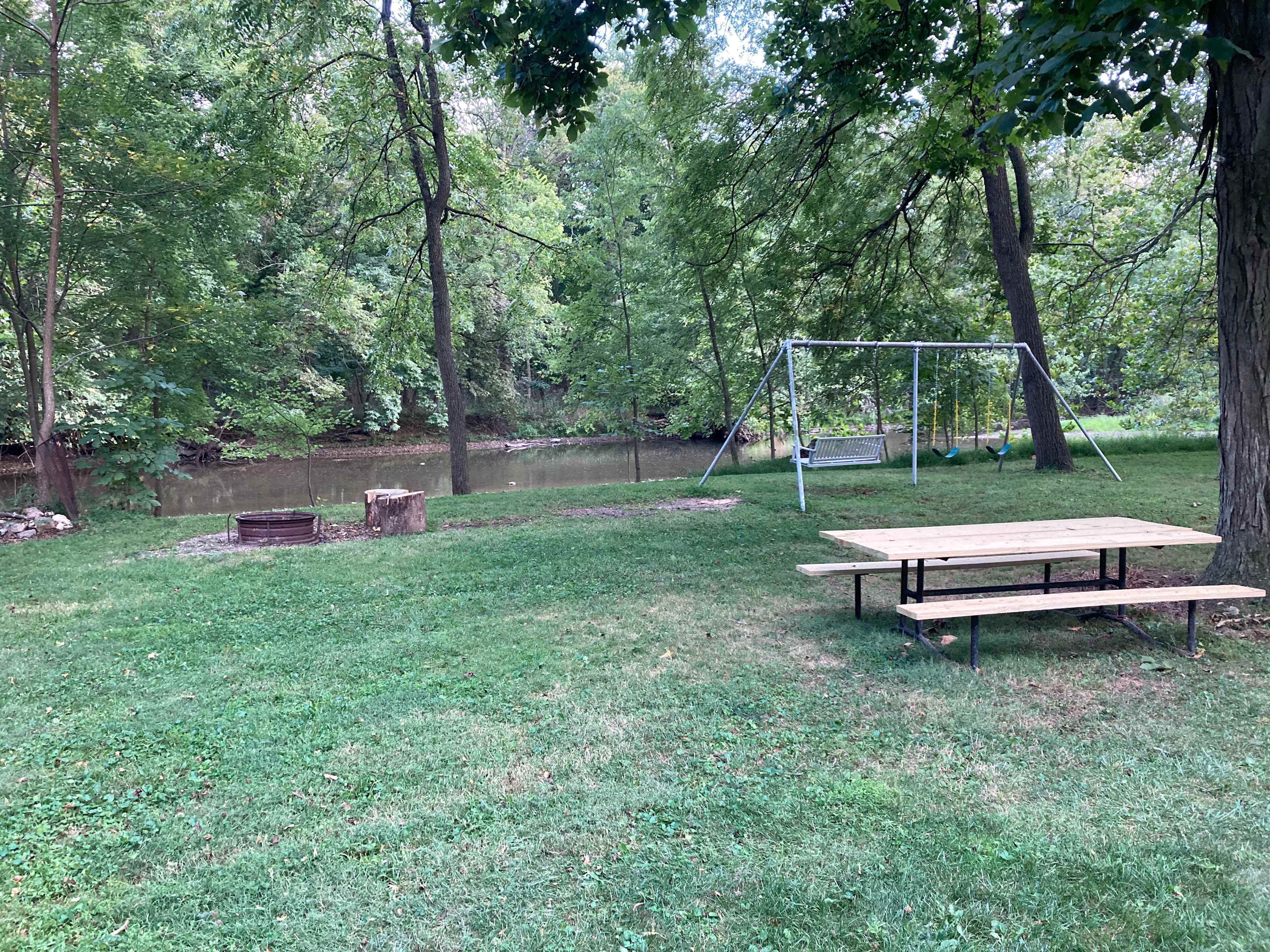 Swingset, porch swing, fire pit and picnic table overlooking the Creek