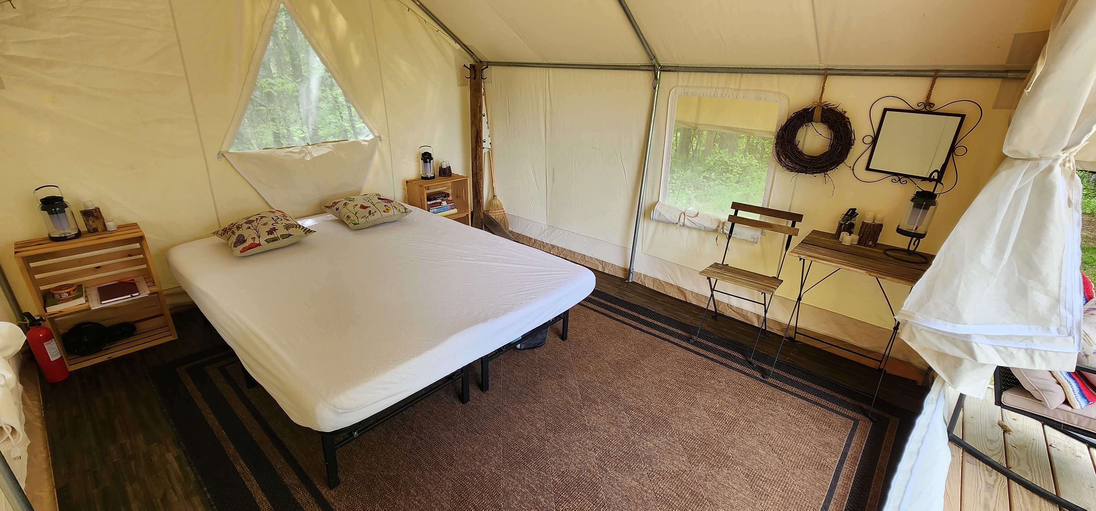 Inside of platform tent has a queen size bed, table & chairs, side tables with games, and a coat rack. In colder months we also have a propane heater.