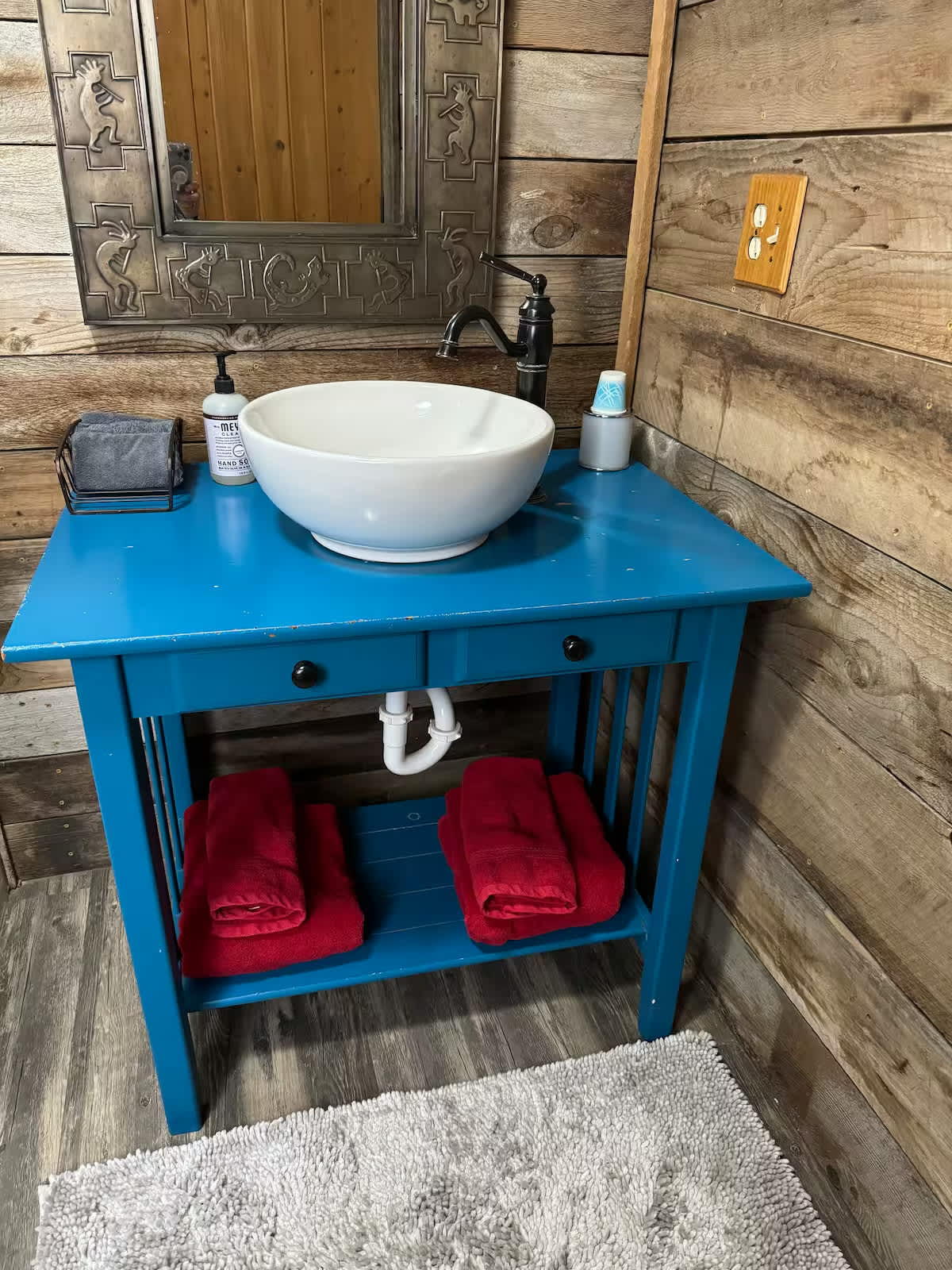 THE BATHROOM VANITY. It's an original, using an old baker's rack and new sink and fixtures. 
And, of course, that walls are aged, repurposed wood.