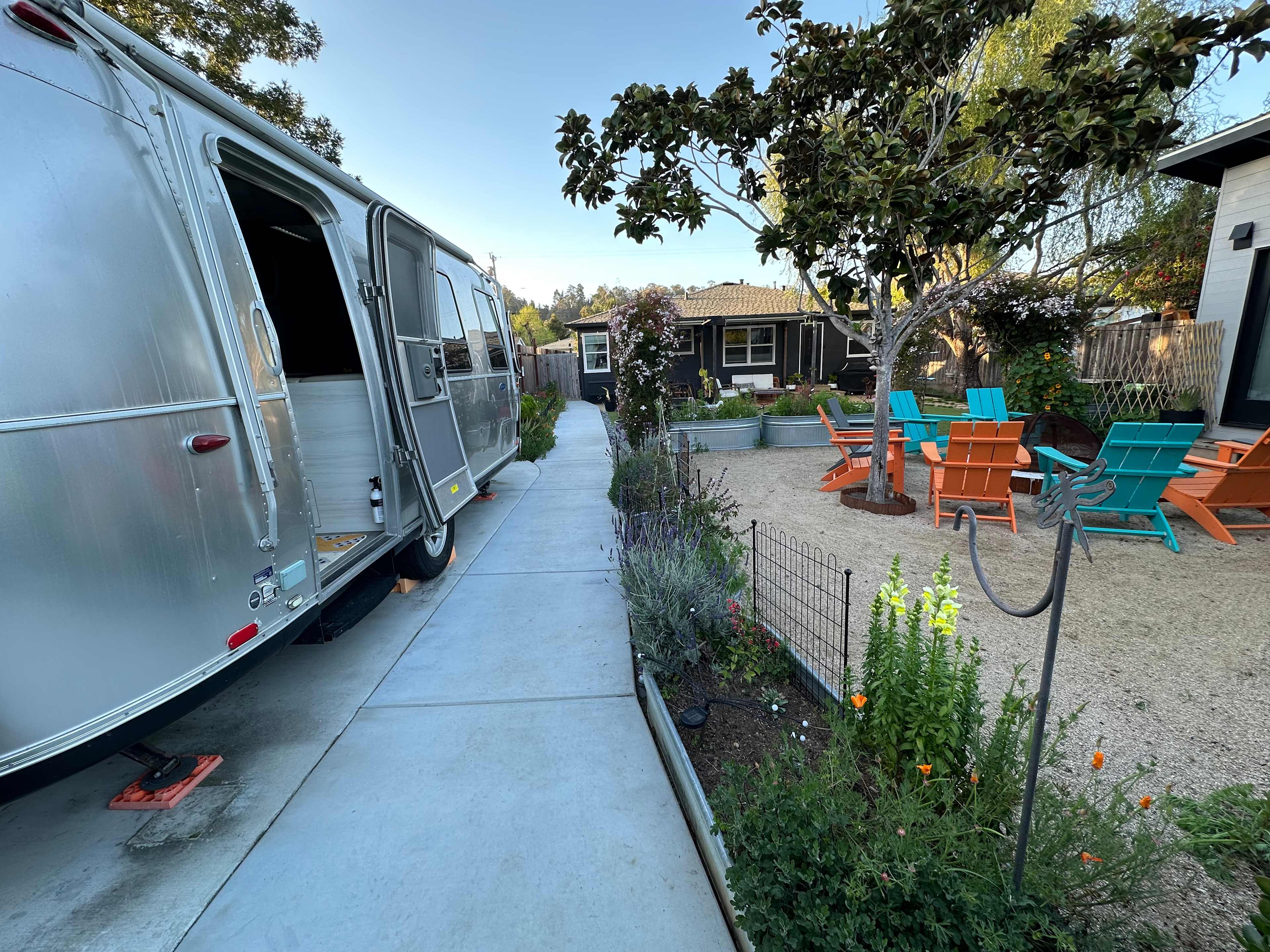 The Airstream sits between the main front house and rear ADU in a large shared yard and garden. (This is the view from the back gate to the ADU, looking towards the shared yard, airstream, and firepit).
