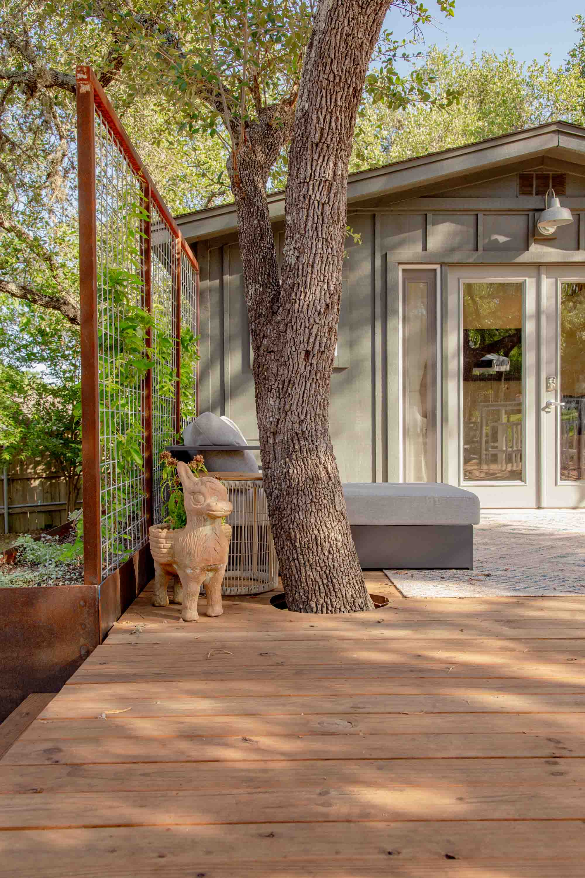 Charming details like the planted donkey statue and a tree growing through the deck add character and whimsy to this peaceful retreat.