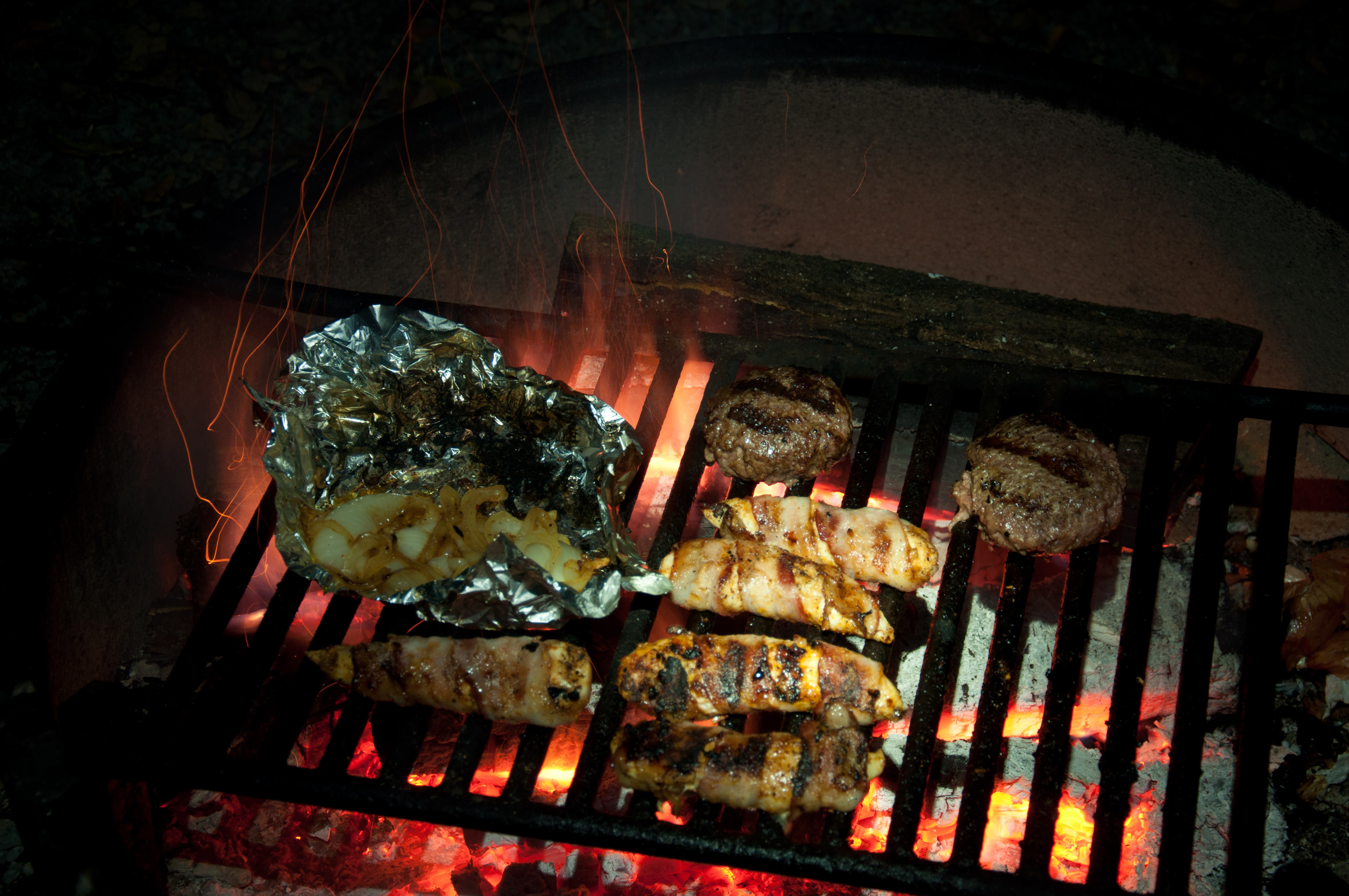 Dinner over the campfire, bacon wrapped chicken strips, burgers and grilled onions