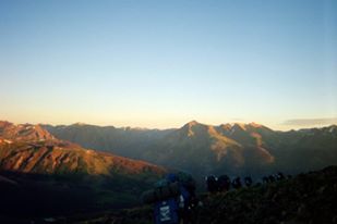 Backpacking in the summer as the sun rises to warm our frozen fingers. 