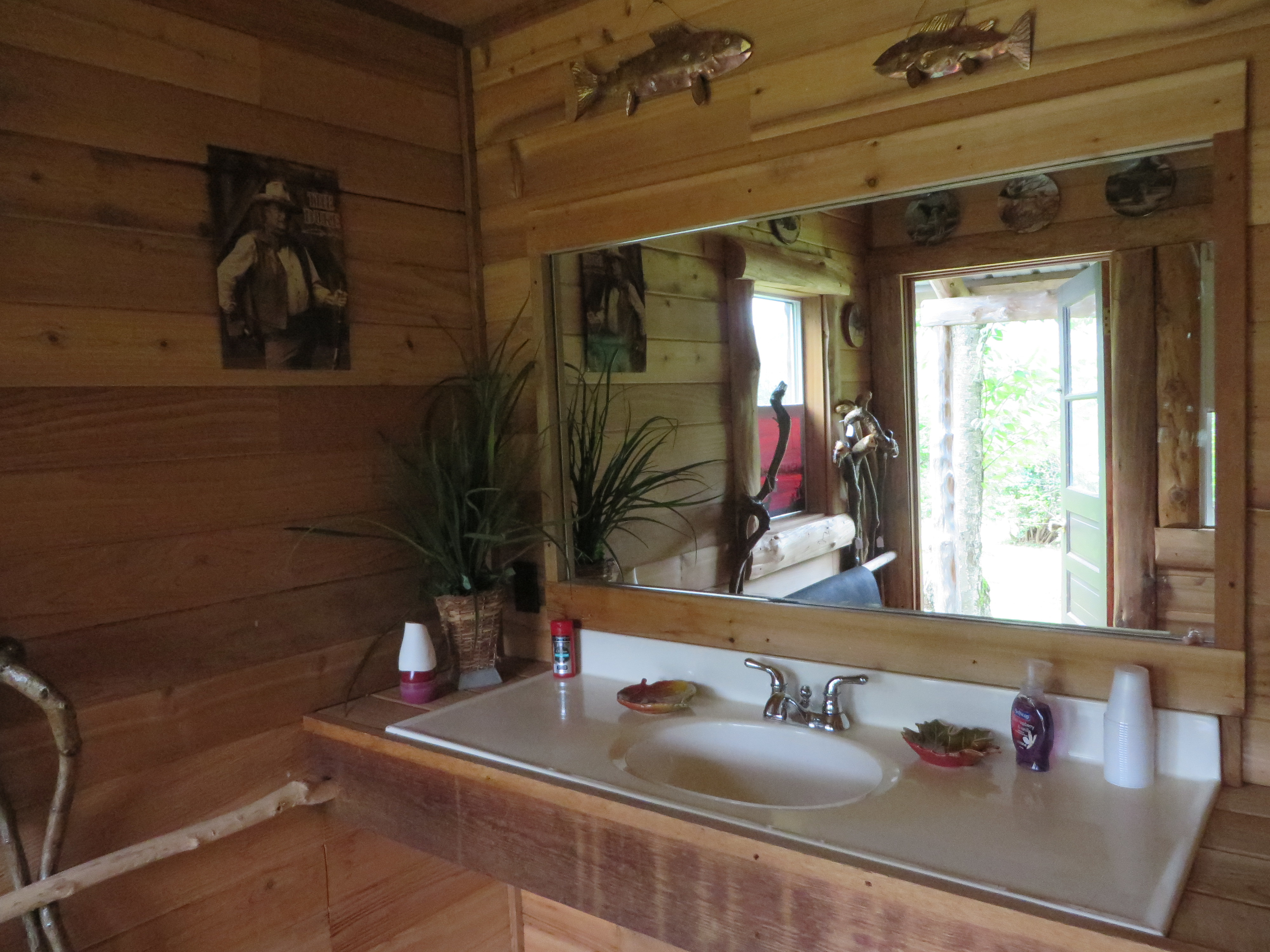 Bath house sink with large, shareable mirror, caddy storage, and electrical outlets.