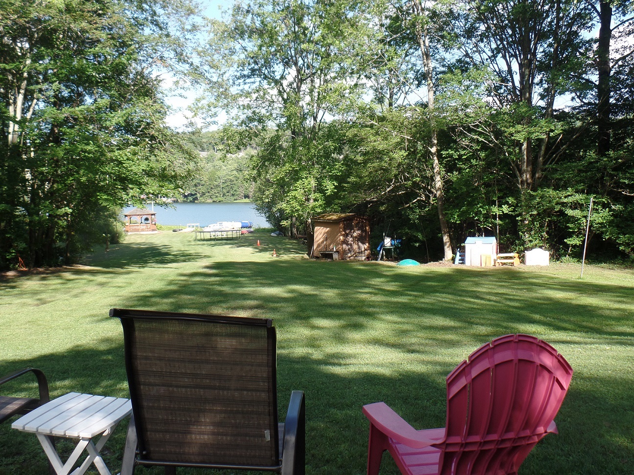 View from top of lawn when you walk around cottage from the parking area.  Campfire is to your right.  Shady, more private camping spots off to left of lawn, across footbridge.