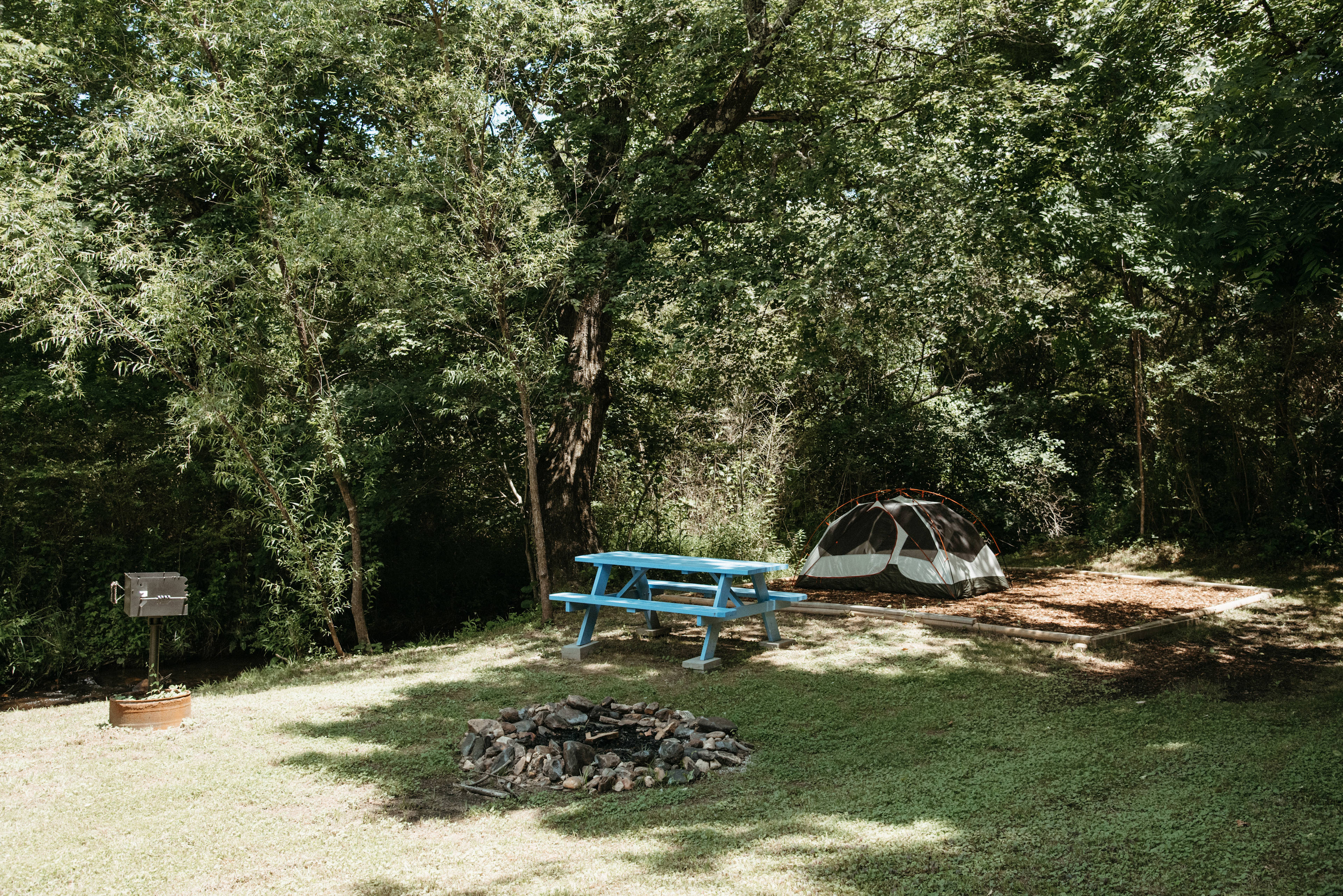 Campsite has a nice picnic table, fire pit, tent platform, and a grill.
