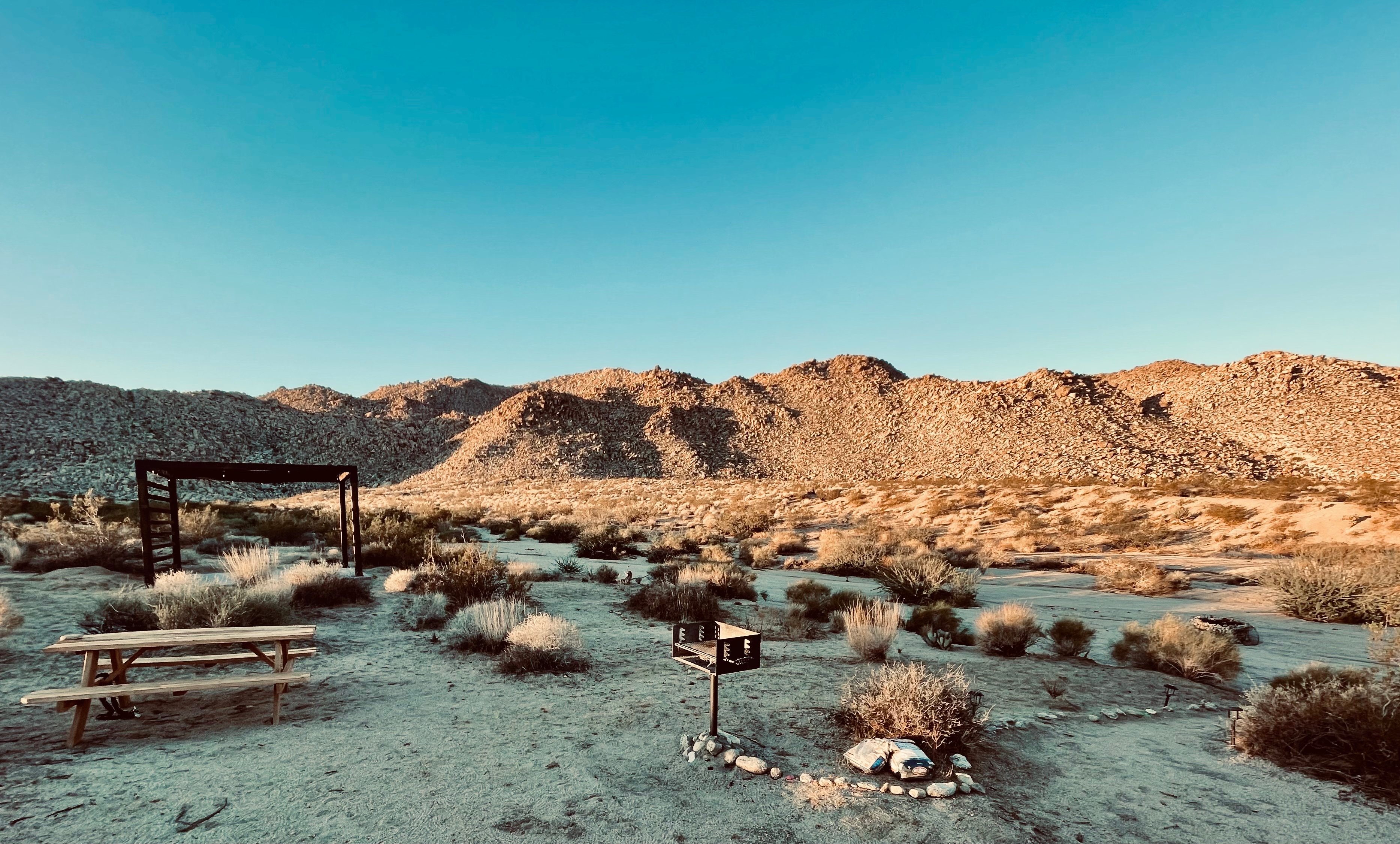 Morning sun rays providing a camp overview with Joshua Tree National park mountains as the backdrop. 