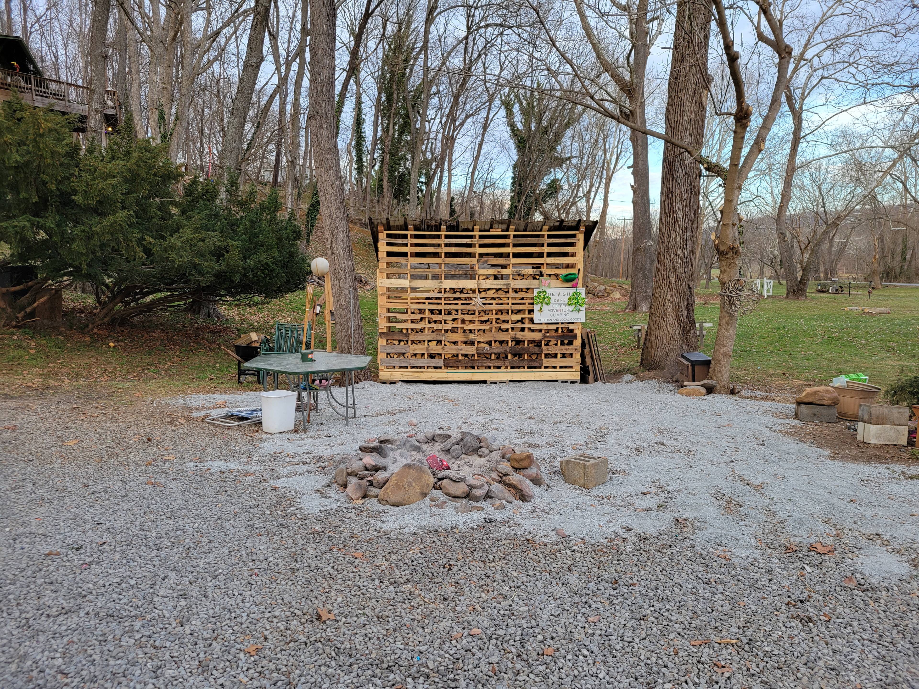 Campside firepit and the firewood shed right next to the hookups. Unlimited firewood provided for $25 a day. On the backside of this shed hang two sit on top kayaks, needed gear, and a wheelbarrow to help move wood to the riverside firepit. 
