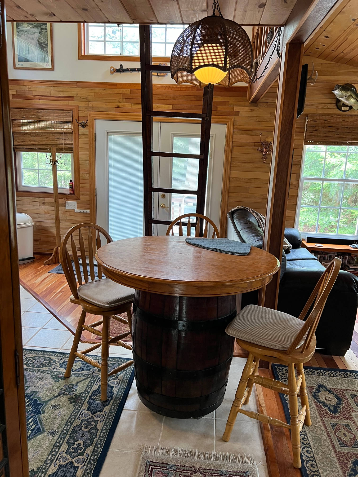Open area showing table, chairs, ladder to sleeping loft, sleeping couch and front door to outside.