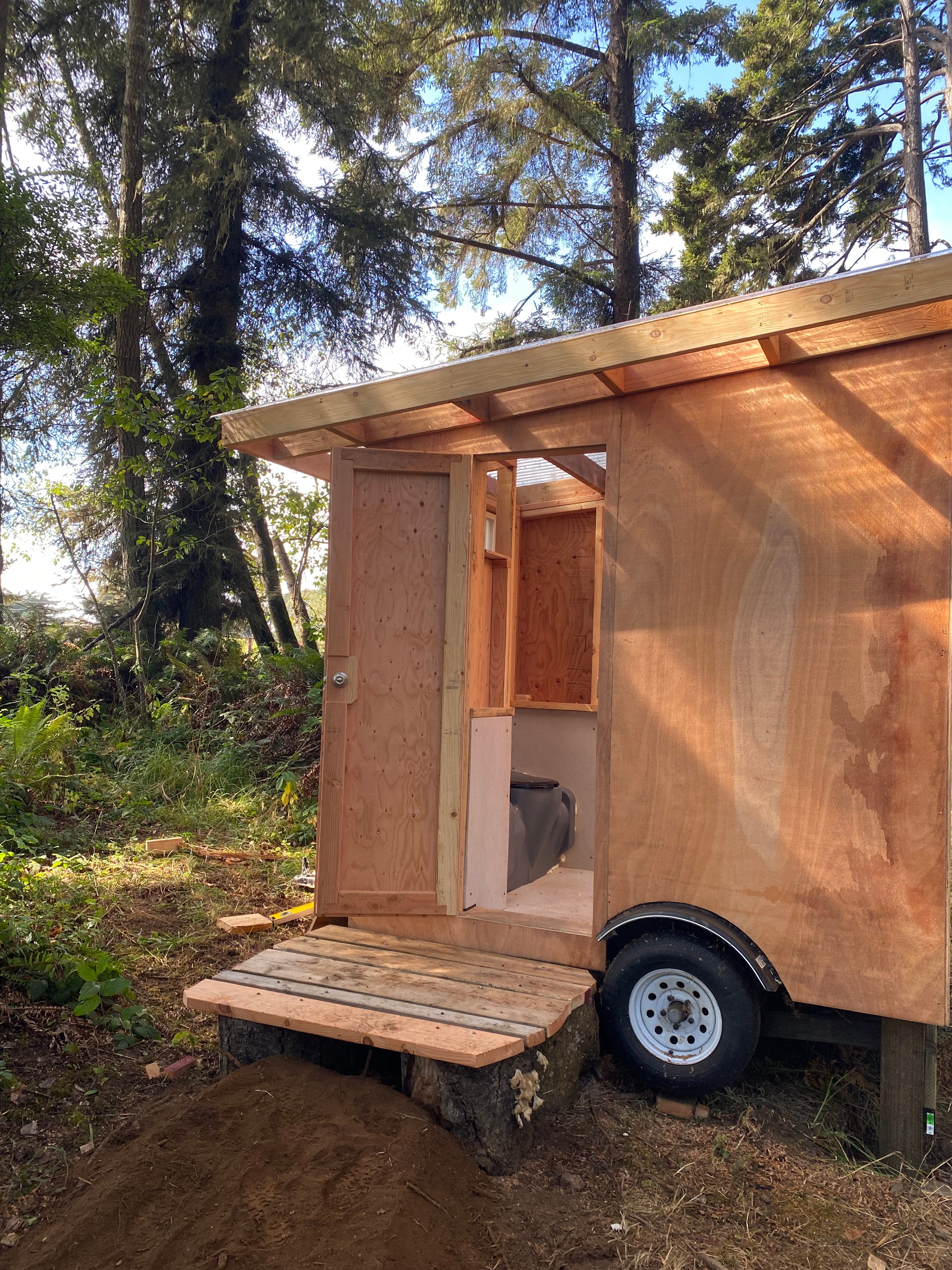 Our homemade toilet room is nice and clean, has electric lights, outlets to charge your digital things, and a snug little closet where you are welcome to store things during your stay.
And it has a clear roof so you can look up at the trees from inside!