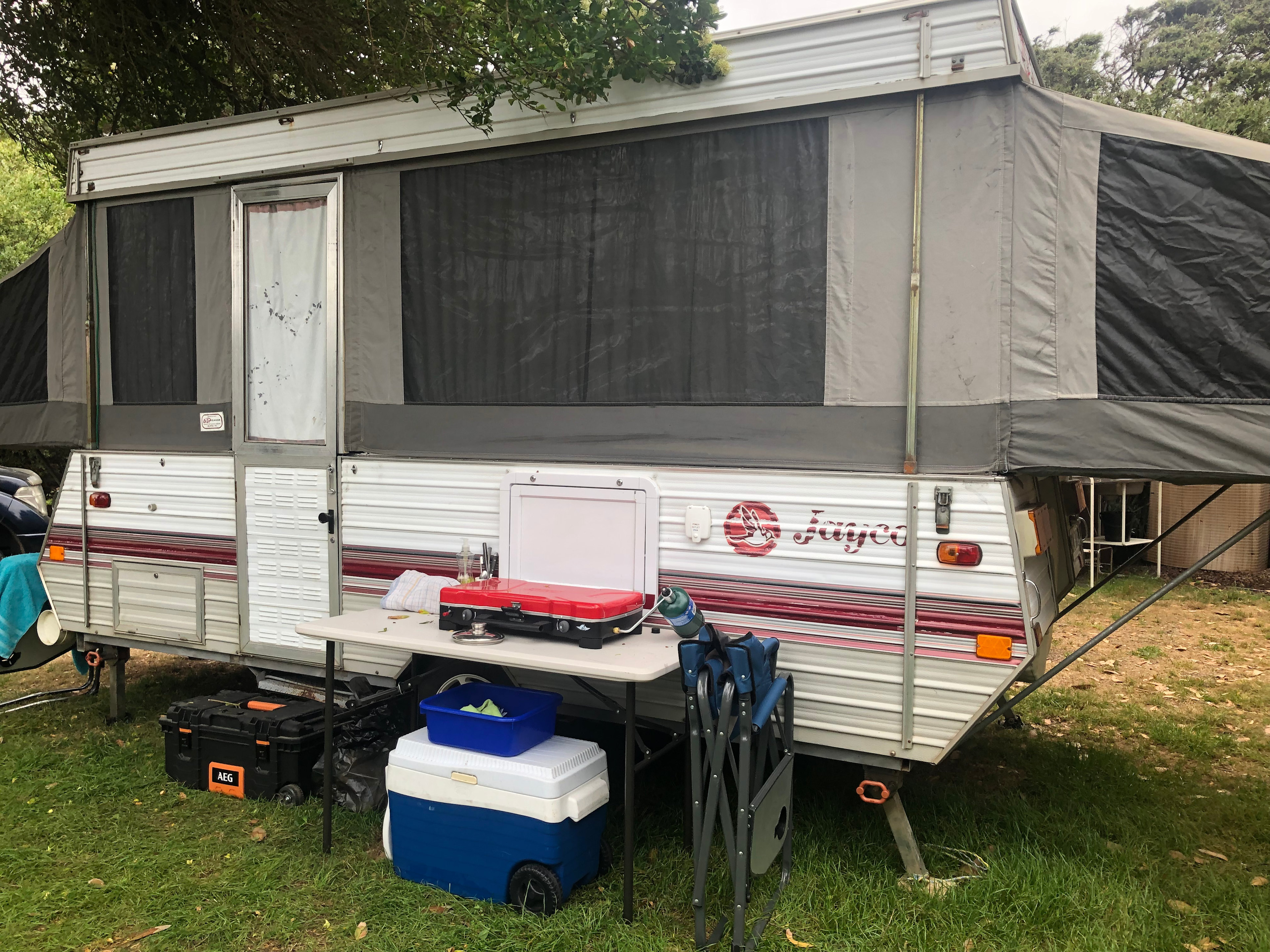 Camper at front of black and there is shade from a tree out front. Behind is kitchen and shower so enough privacy.there is houses either side of this block. 