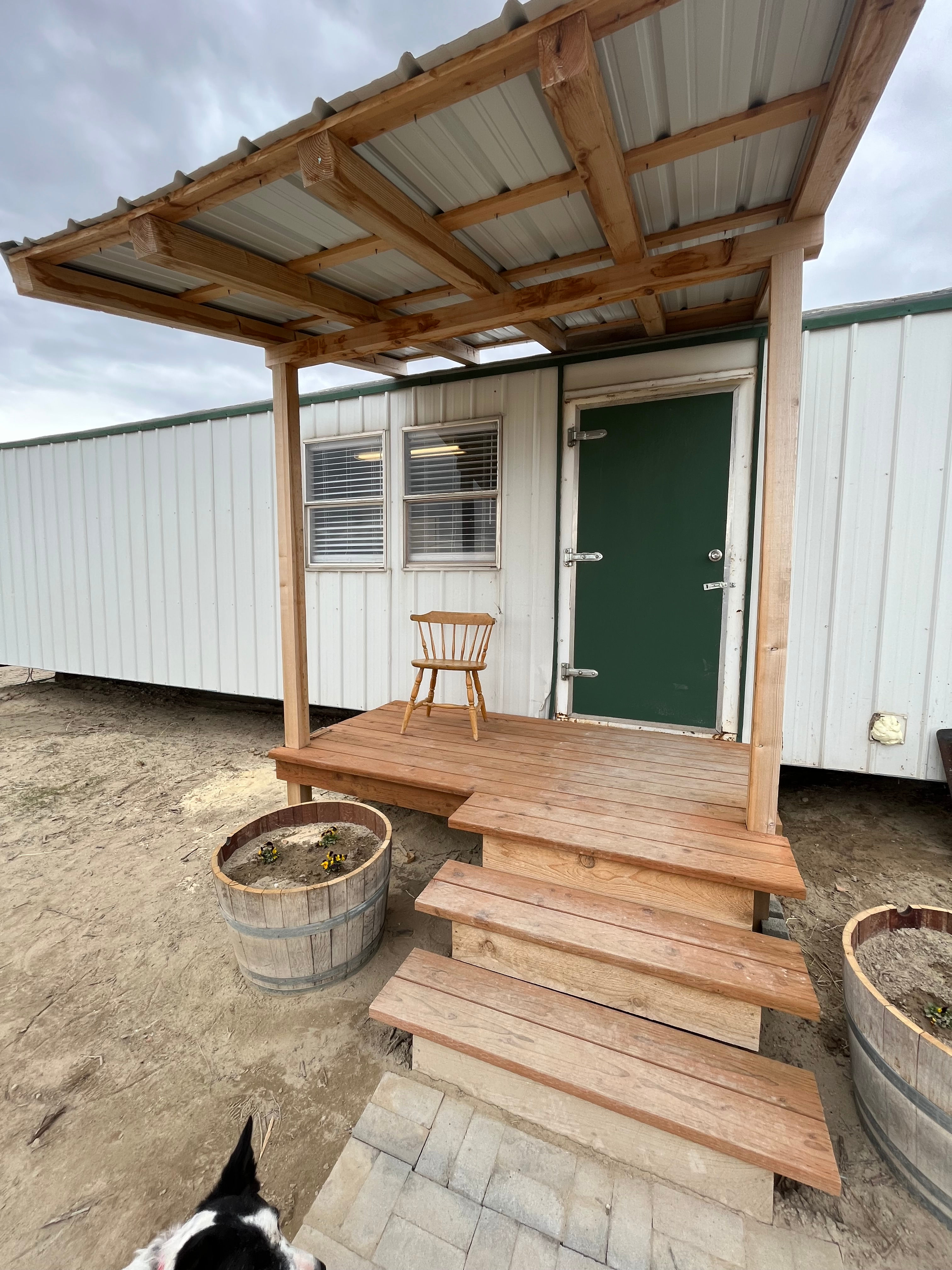 The little front porch with a chair and pansy in the wine barrels. This picture is taken very early spring, March 23, 2023
