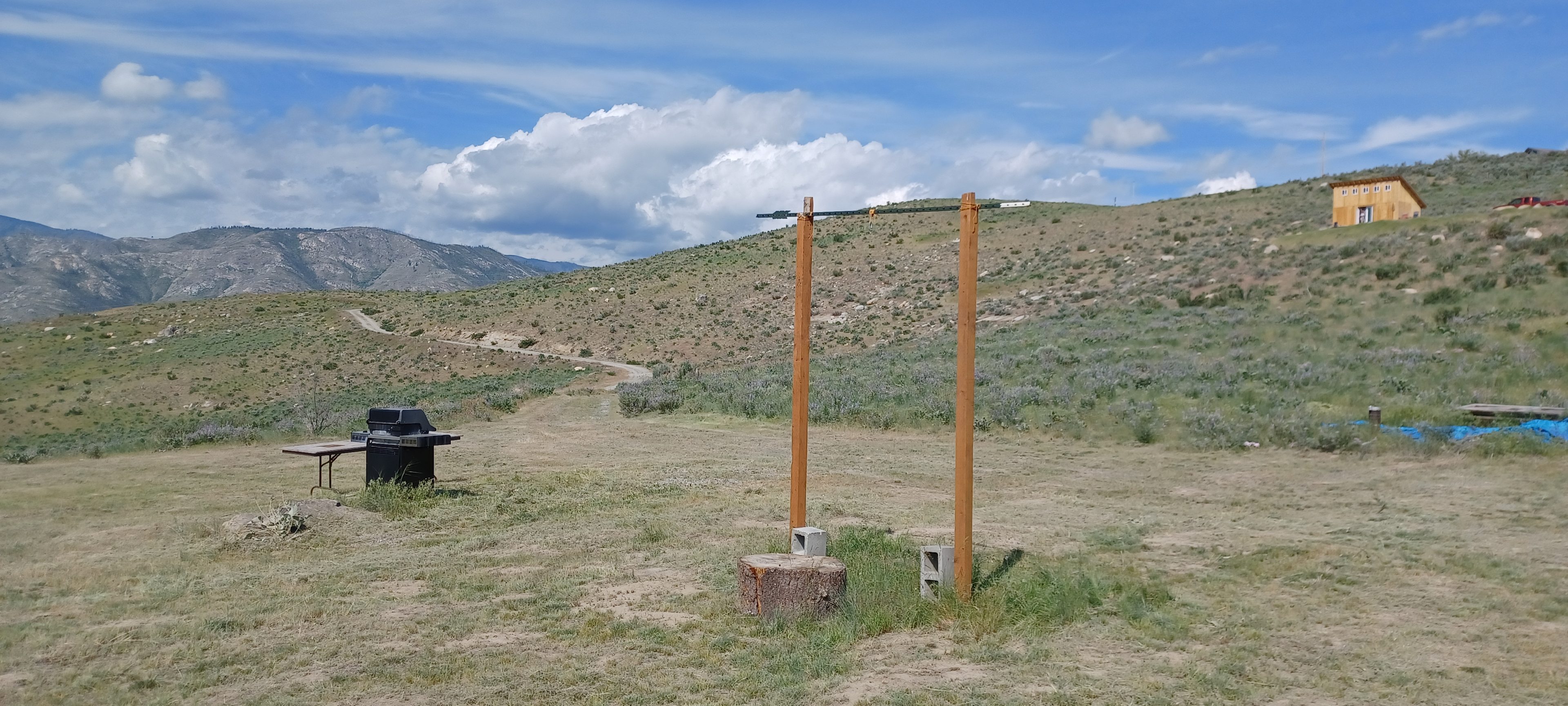 View of the campsite with the propane grill, table and a rack you can hang whatever you want! An outdoor shower, clothes, or the days hunt. 
