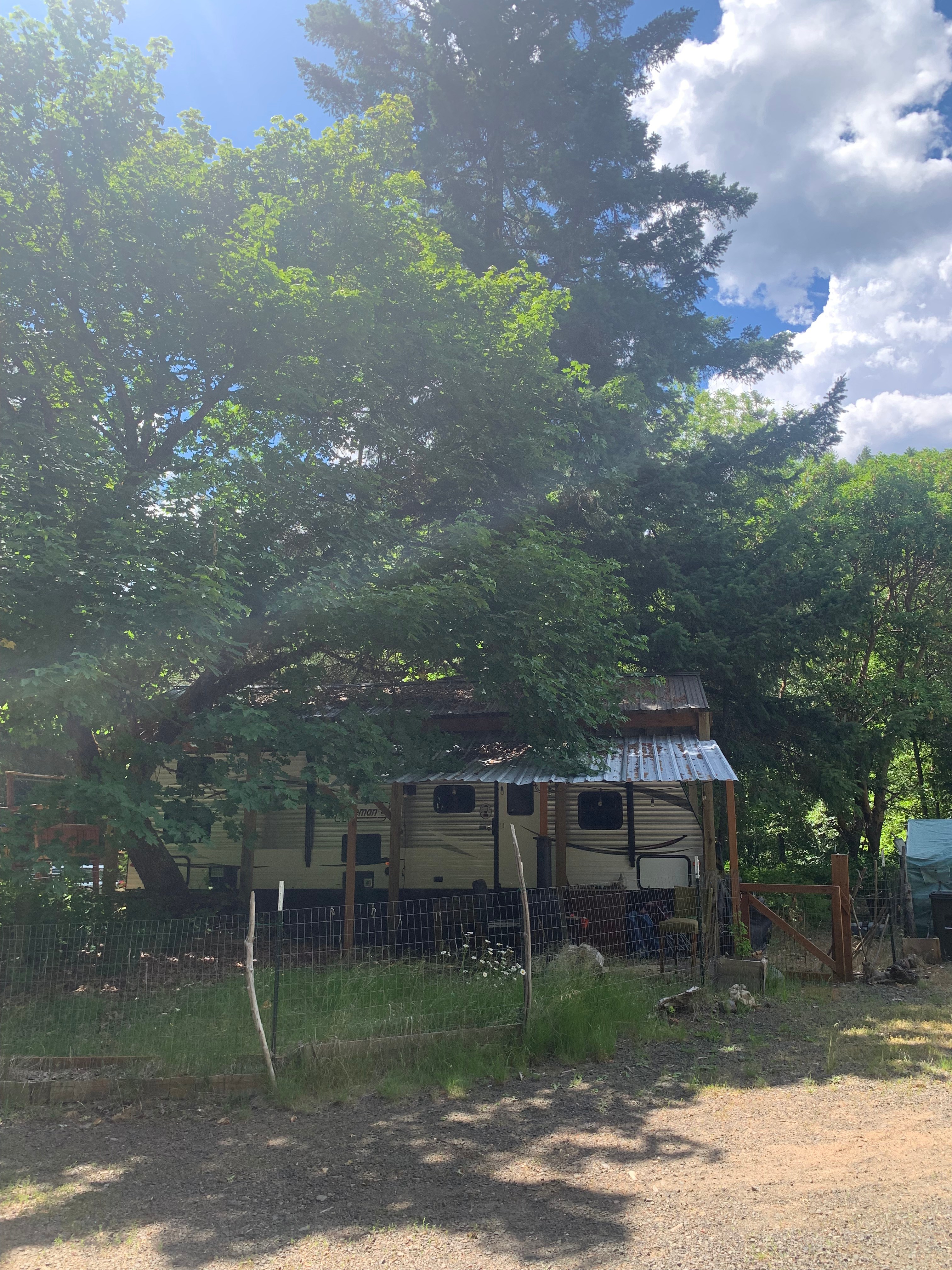 Situated under a cover and shaded by gorgeous trees. Small covered area in front with a seasonal fire pit and chairs.