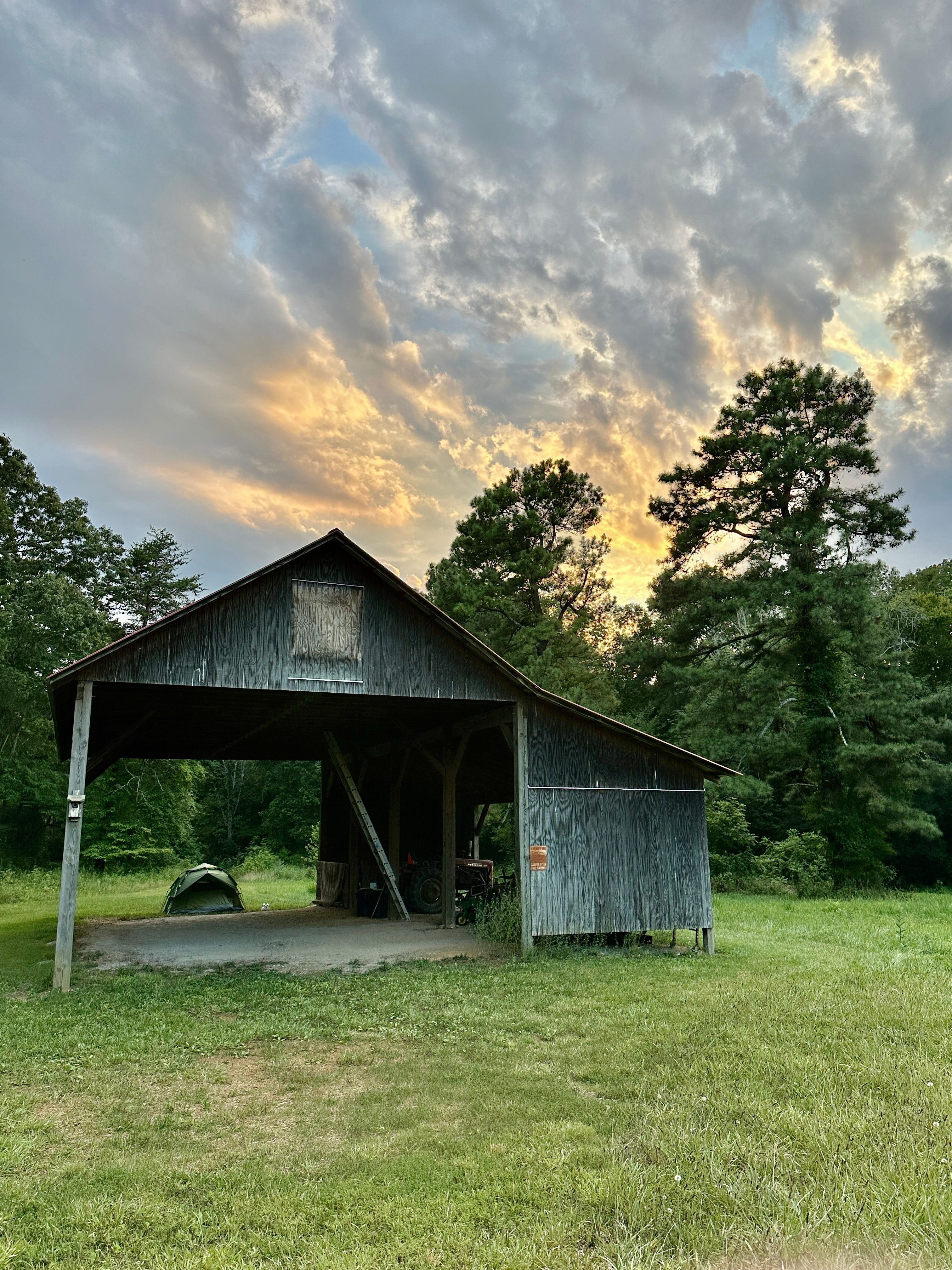 Barn structure and tent set up in private meadow behind it 