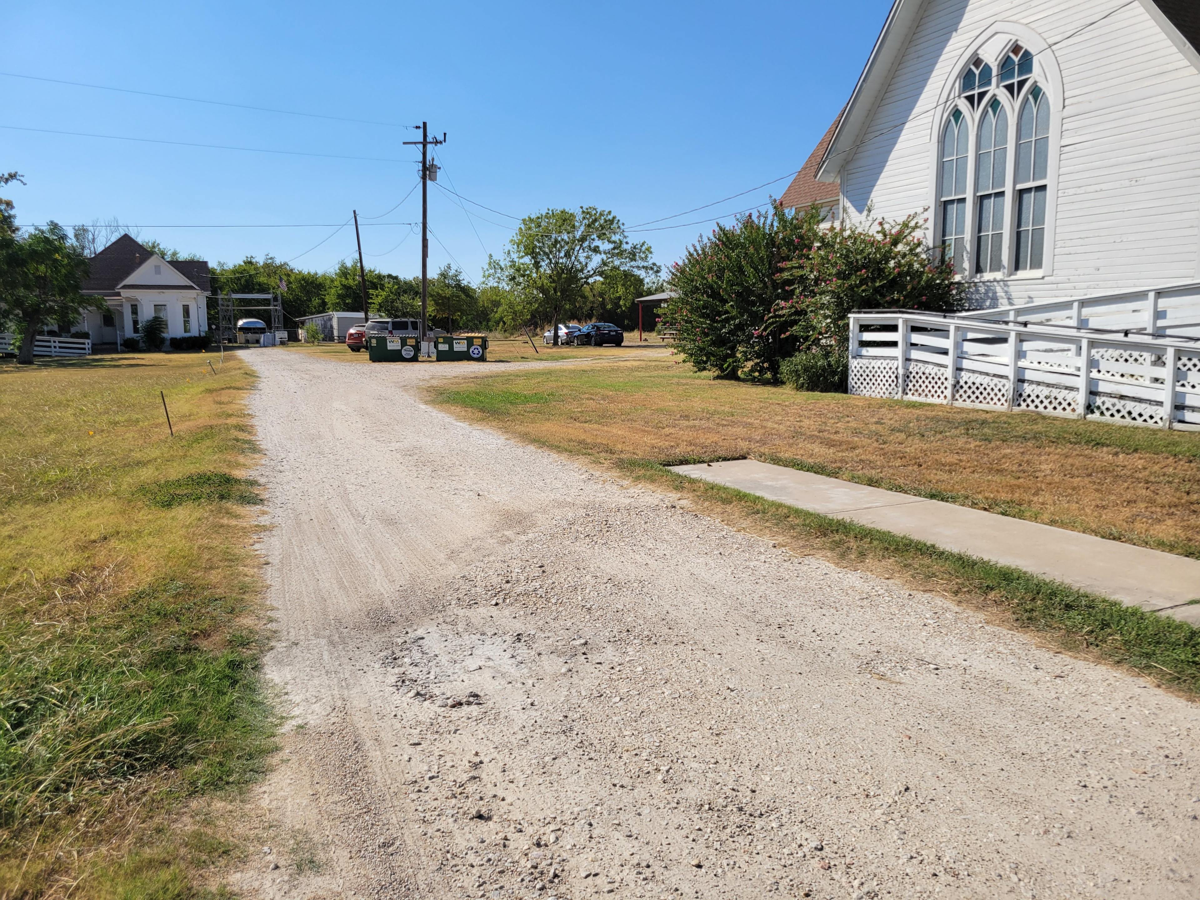 Continue down the driveway to the left of the church, and take the right in front of the dumpsters and light pole.