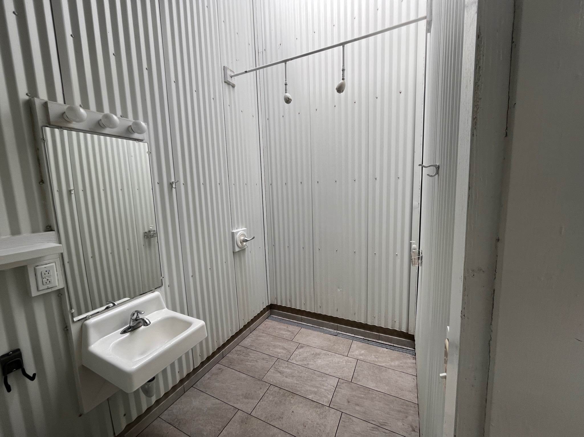 Oversided bathroom with dual shower head. Natural light above.