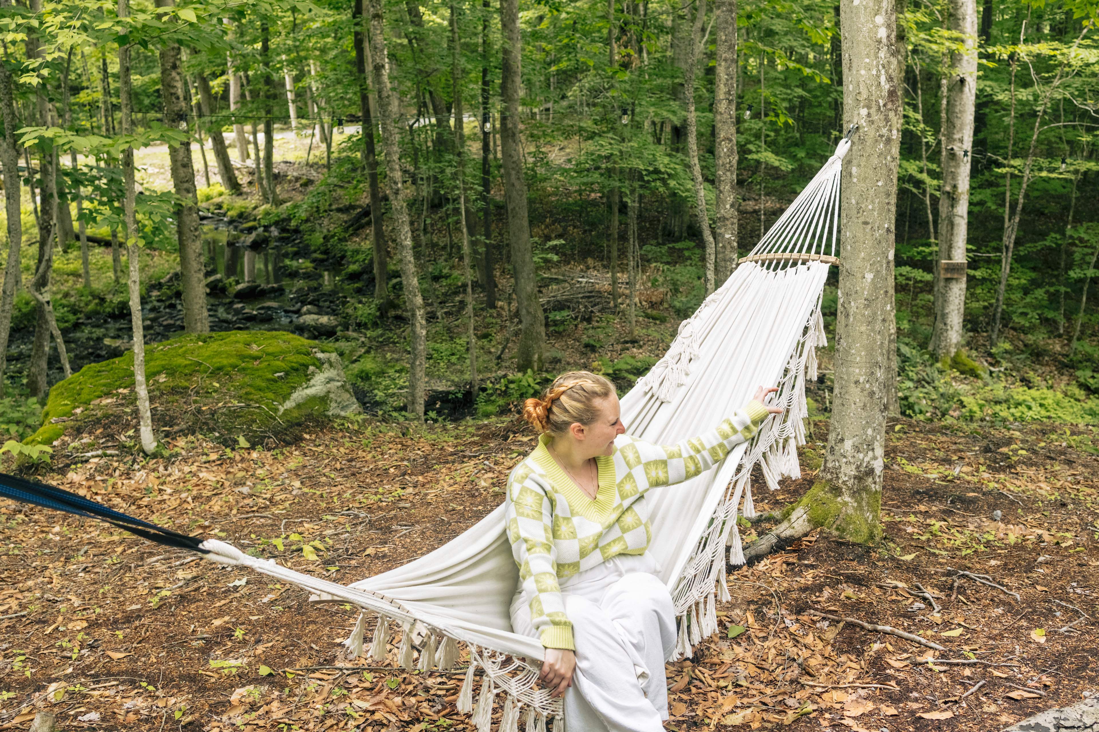 The hammock sits by the stream. 