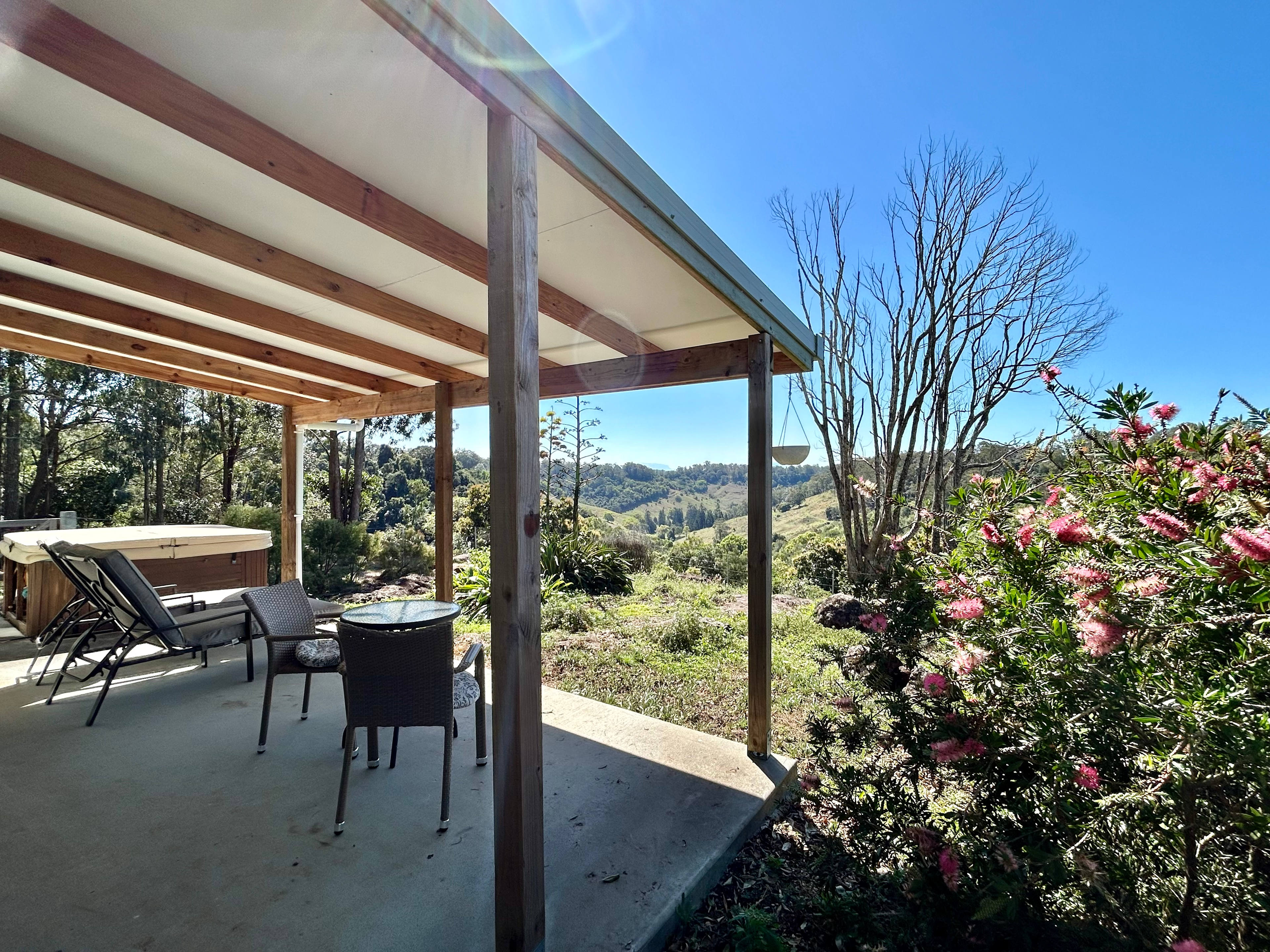 Furnished patio between the spa and bottlebrush trees, with views to the Border Ranges National Park.