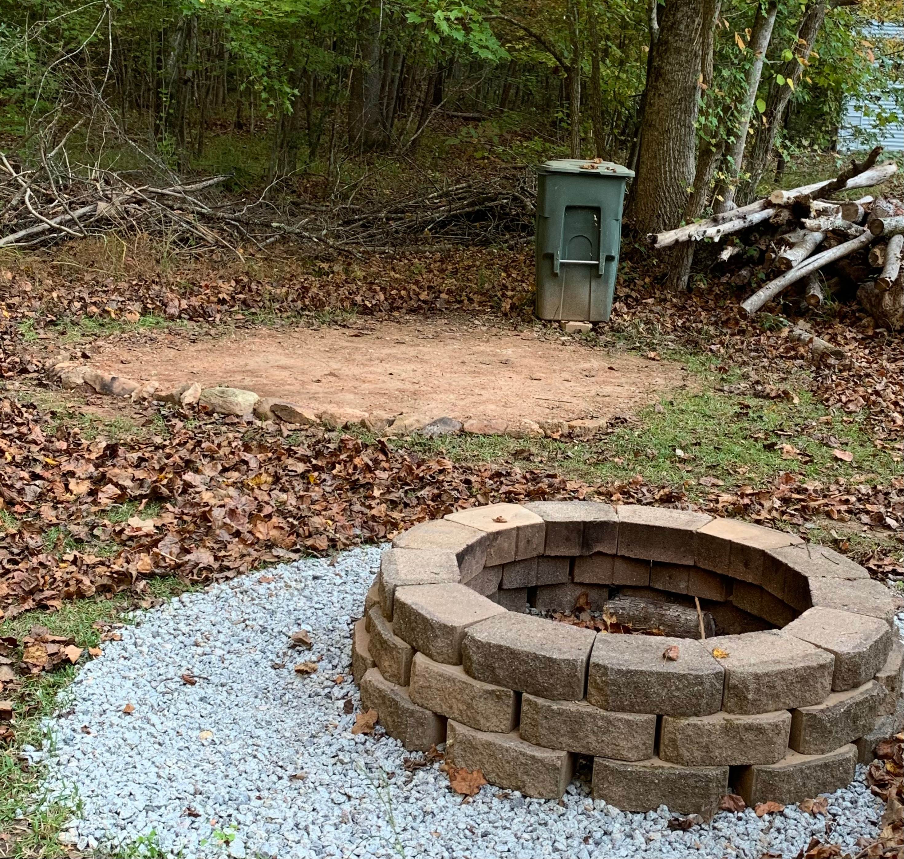 Fire pit with first tent site option in the background - leveled dirt area bordered with rocks