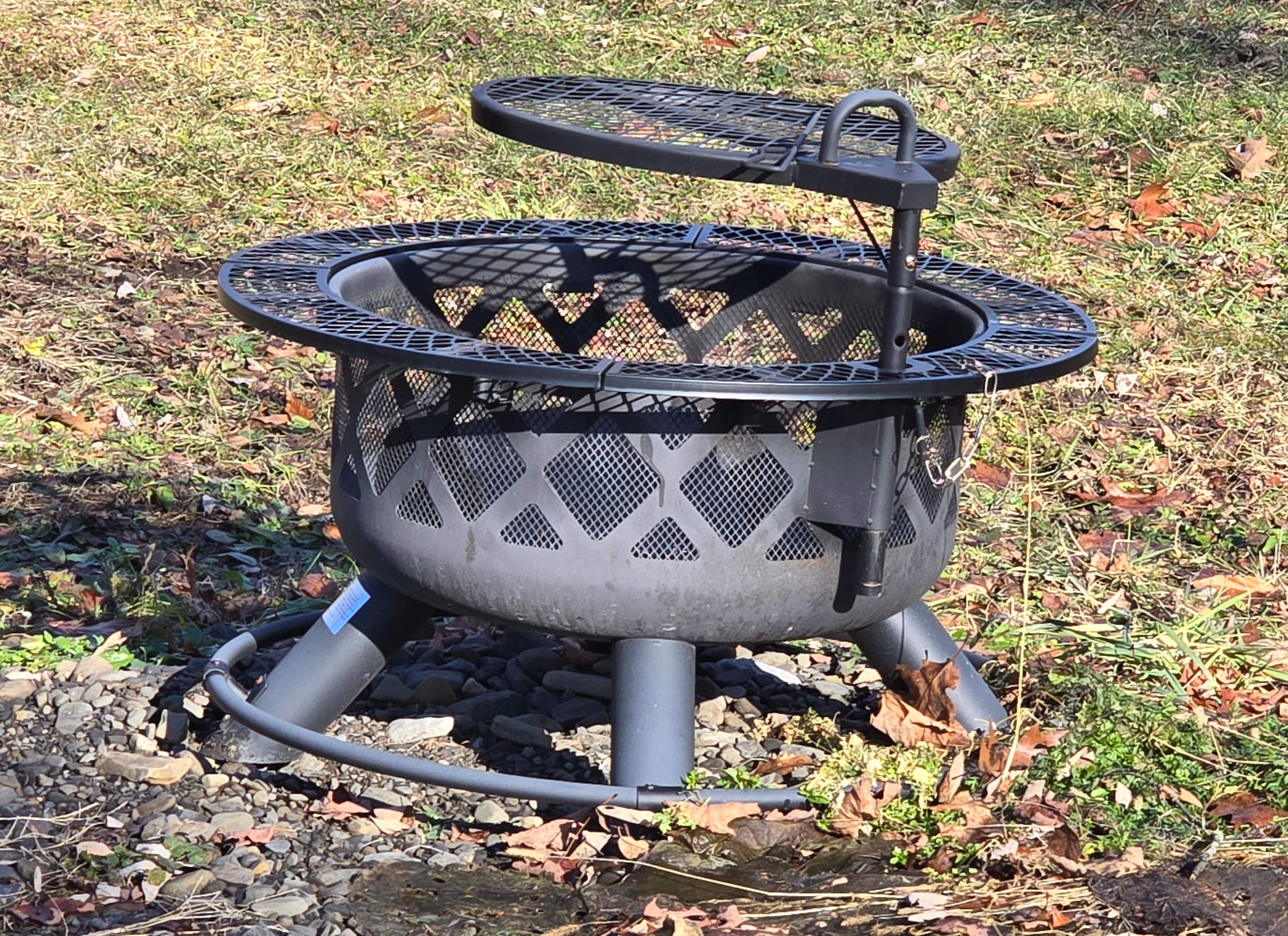 A fire pit in front of the cabin, with an attached grill for cooking on.
