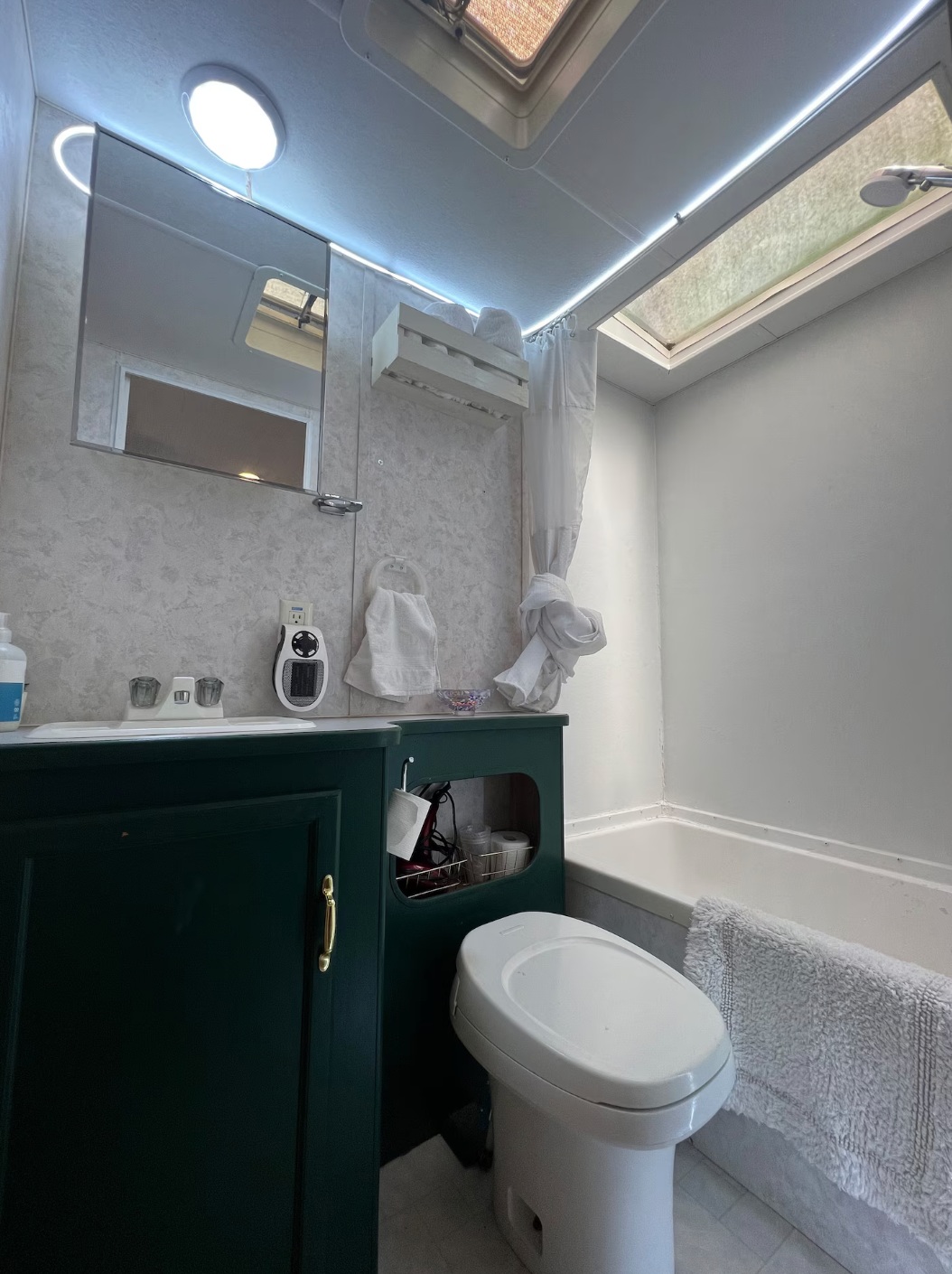 Two skylights in the bathroom. Wall shower dispenser with shampoo, conditioner and body wash. Hair dryer and towels also provided. Toilet flushes with a hand lever on the right-facing side.