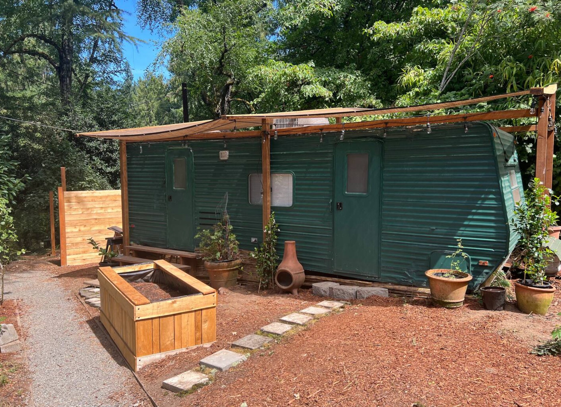 Sidewalk leads to the main house, left of photo. Privacy fence keeps all neighbors out of eye sight on this one-acre property. The flowerboxes now have tall bamboo and the sunshade awning has been upgraded to green corrugated roofing! We're always improving between guests (new pics soon)
