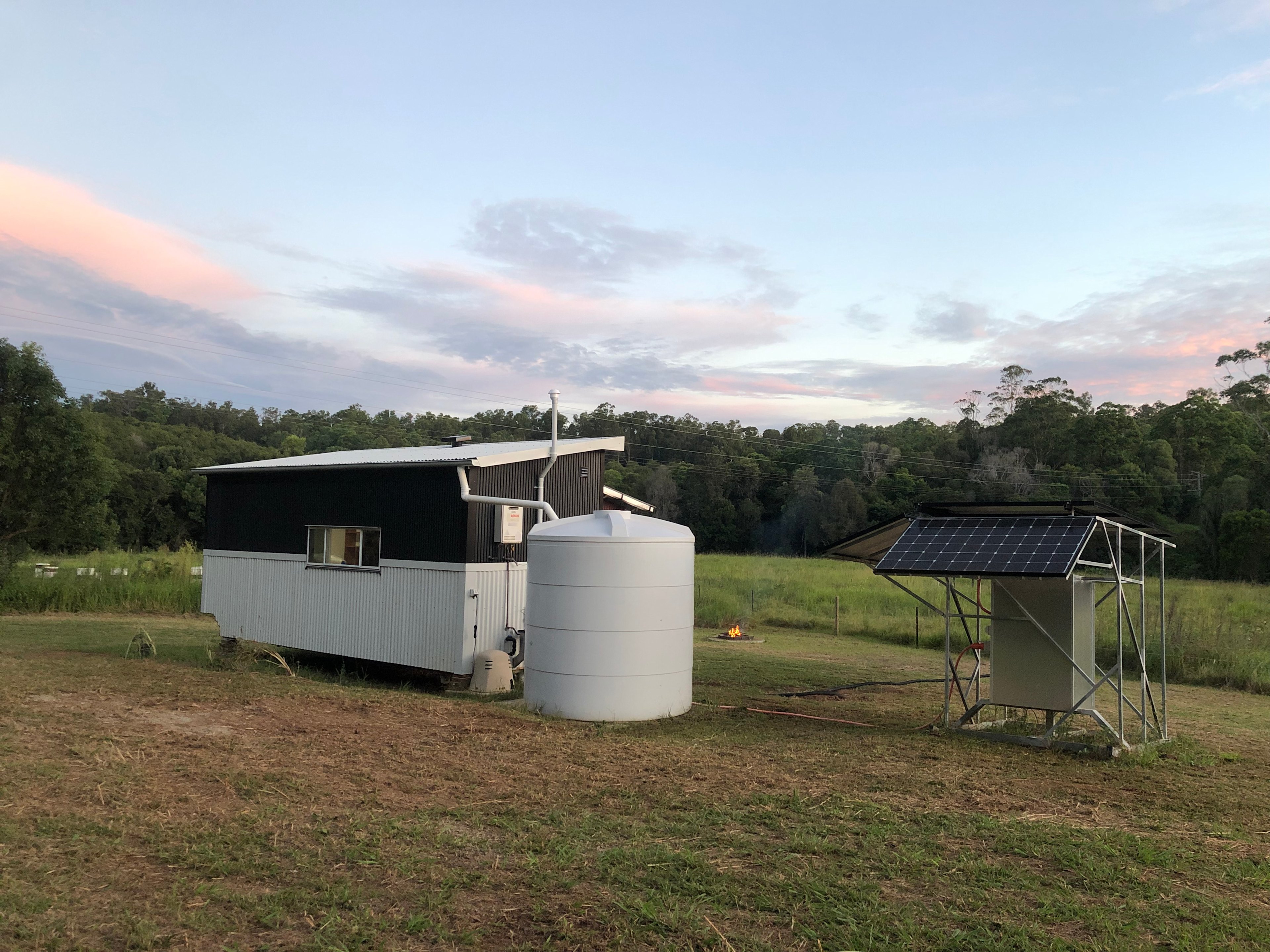 Rear side of tiny house with beehive paddock on the left and power station on the right.
